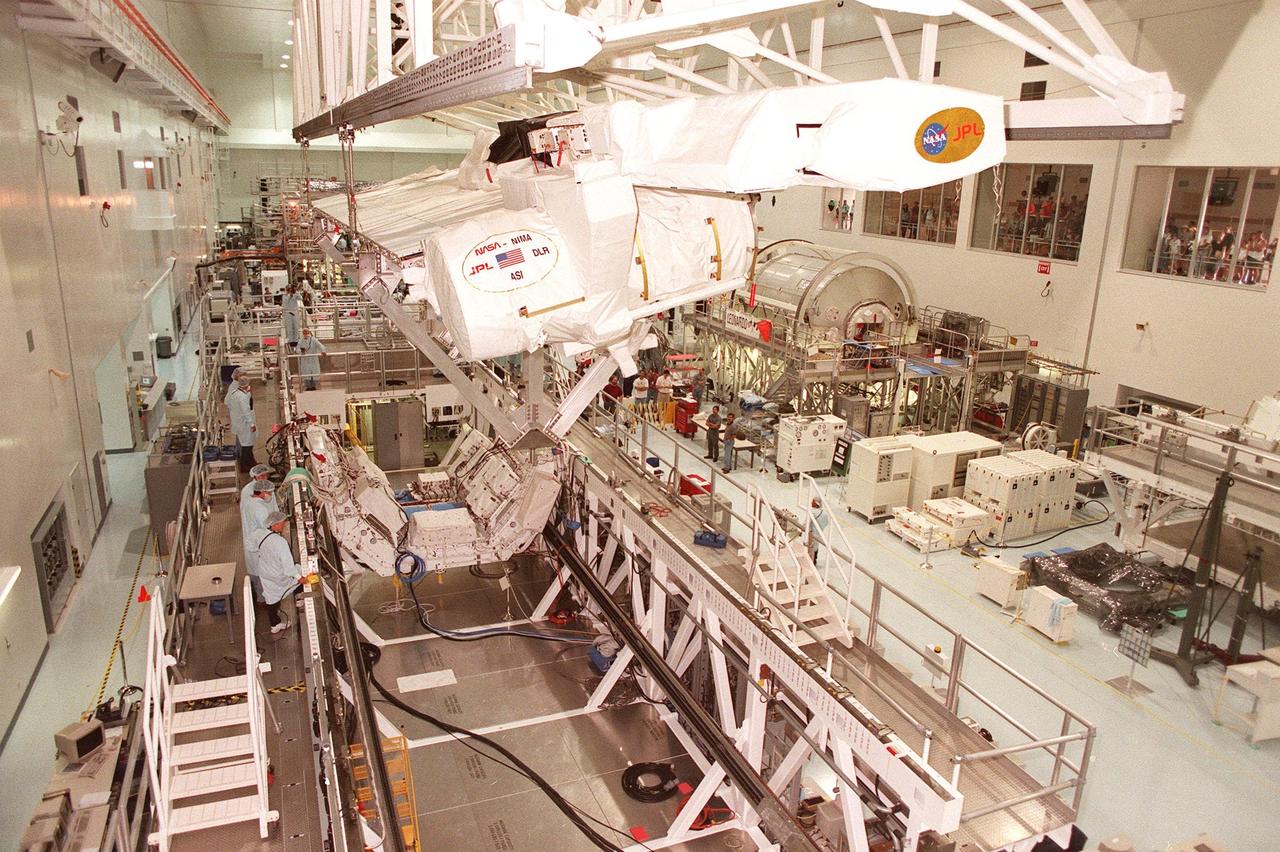 Inside the Space Station Processing Facility, the Shuttle Radar Topography Mission (SRTM) is maneuvered by an overhead crane toward a workstand below. The SRTM, which is the primary payload on mission STS-99, consists of a specially modified radar system that will fly onboard the Space Shuttle during the 11-day mission scheduled for launch in September 1999. The objective of this radar system is to obtain the most complete high-resolution digital topographic database of the Earth. It will gather data that will result in the most accurate and complete topographic map of the Earth's surface that has ever been assembled. SRTM is an international project spearheaded by the National Imagery and Mapping Agency and NASA, with participation of the German Aerospace Center DLR. SRTM will be making use of a technique called radar interferometry, wherein two radar images are taken from slightly different locations. Differences between these images allow for the calculation of surface elevation, or change. To get two radar images taken from different locations, the SRTM hardware will consist of one radar antenna in the shuttle payload bay and a second radar antenna attached to the end of a mast extended 60 meters (195 feet) out from the shuttle