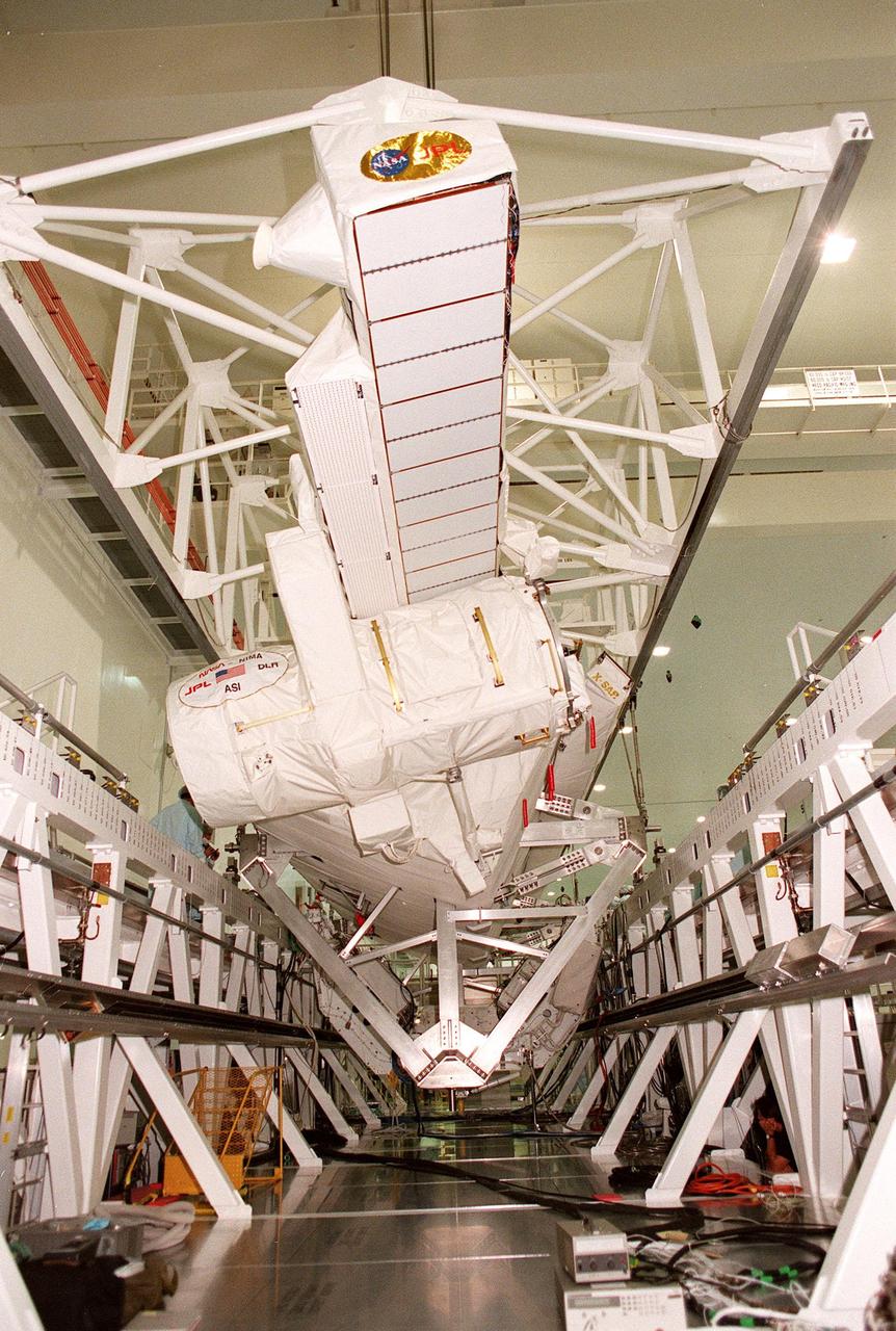 The move of the Shuttle Radar Topography Mission (SRTM) is nearly complete as it is lowered onto the workstand in the Space Station Processing Facility. The SRTM, which is the primary payload on mission STS-99, consists of a specially modified radar system that will fly onboard the Space Shuttle during the 11-day mission scheduled for launch in September 1999. The objective of this radar system is to obtain the most complete high-resolution digital topographic database of the Earth. It will gather data that will result in the most accurate and complete topographic map of the Earth's surface that has ever been assembled. SRTM is an international project spearheaded by the National Imagery and Mapping Agency and NASA, with participation of the German Aerospace Center DLR. SRTM will be making use of a technique called radar interferometry, wherein two radar images are taken from slightly different locations. Differences between these images allow for the calculation of surface elevation, or change. To get two radar images taken from different locations, the SRTM hardware will consist of one radar antenna in the shuttle payload bay and a second radar antenna attached to the end of a mast extended 60 meters (195 feet) out from the shuttle