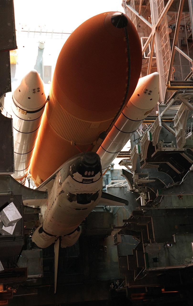 KENNEDY SPACE CENTER, FLA. -- The Space Shuttle Discovery, dwarfed by its external tank and solid rocket boosters, is in position in High Bay 1 of the Vehicle Assembly Building for repair of damage to the external tank's foam insulation caused by hail. The Shuttle was rolled back from Pad 39B this morning because access to all of the damaged areas was not possible at the pad. The work is expected to take two to three days, allowing Discovery to roll back to the pad by midweek for launch of mission STS-96, the 94th launch in the Space Shuttle Program. This is only the 13th time since 1981 that a Shuttle has had to roll back from the pad. Liftoff will occur no earlier than May 27. STS-96 is a logistics and resupply mission for the International Space Station, carrying such payloads as a Russian crane, the Strela; a U.S.-built crane; the Spacehab Oceaneering Space System Box (SHOSS), a logistics items carrier; and STARSHINE, a student-shared experiment