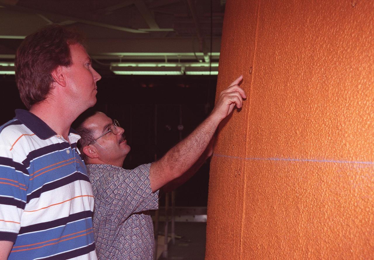 KENNEDY SPACE CENTER, FLA. -- Inside High Bay 1 of the Vehicle Assembly Building (VAB) John Blue, with United Space Alliance, and Jorge Rivera, with NASA, look at the dings in the foam insulation on the external tank of Space Shuttle Discovery. About 150 dings were caused by hail during recent storms. The Shuttle was rolled back from Pad 39B to the VAB for repairs because access to all of the damaged areas was not possible at the pad. The work is expected to take two to three days, allowing Discovery to roll back to the pad as early as May 20 for launch of mission STS-96, the 94th launch in the Space Shuttle Program. Liftoff will occur no earlier than May 27. STS-96 is a logistics and resupply mission for the International Space Station, carrying such payloads as a Russian crane, the Strela; a U.S.-built crane; the Spacehab Oceaneering Space System Box (SHOSS), a logistics items carrier; and STARSHINE, a student-shared experiment