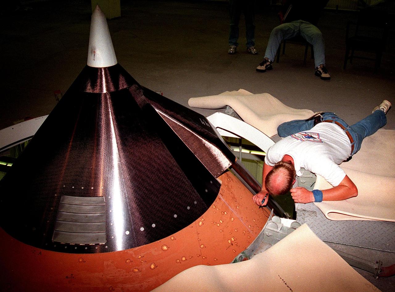 KENNEDY SPACE CENTER, FLA. -- Inside High Bay 1 of the Vehicle Assembly Building (VAB) Mike Sestile, with United Space Alliance, draws circles around divots in the foam insulation on the top of the external tank of Space Shuttle Discovery. About 150 divots were caused by hail during recent storms. The Shuttle was rolled back from Pad 39B to the VAB for repairs because access to all of the damaged areas was not possible at the pad. The work is expected to take two to three days, allowing Discovery to roll back to the pad as early as May 20 for launch of mission STS-96, the 94th launch in the Space Shuttle Program. Liftoff will occur no earlier than May 27. STS-96 is a logistics and resupply mission for the International Space Station, carrying such payloads as a Russian crane, the Strela; a U.S.-built crane; the Spacehab Oceaneering Space System Box (SHOSS), a logistics items carrier; and STARSHINE, a student-shared experiment