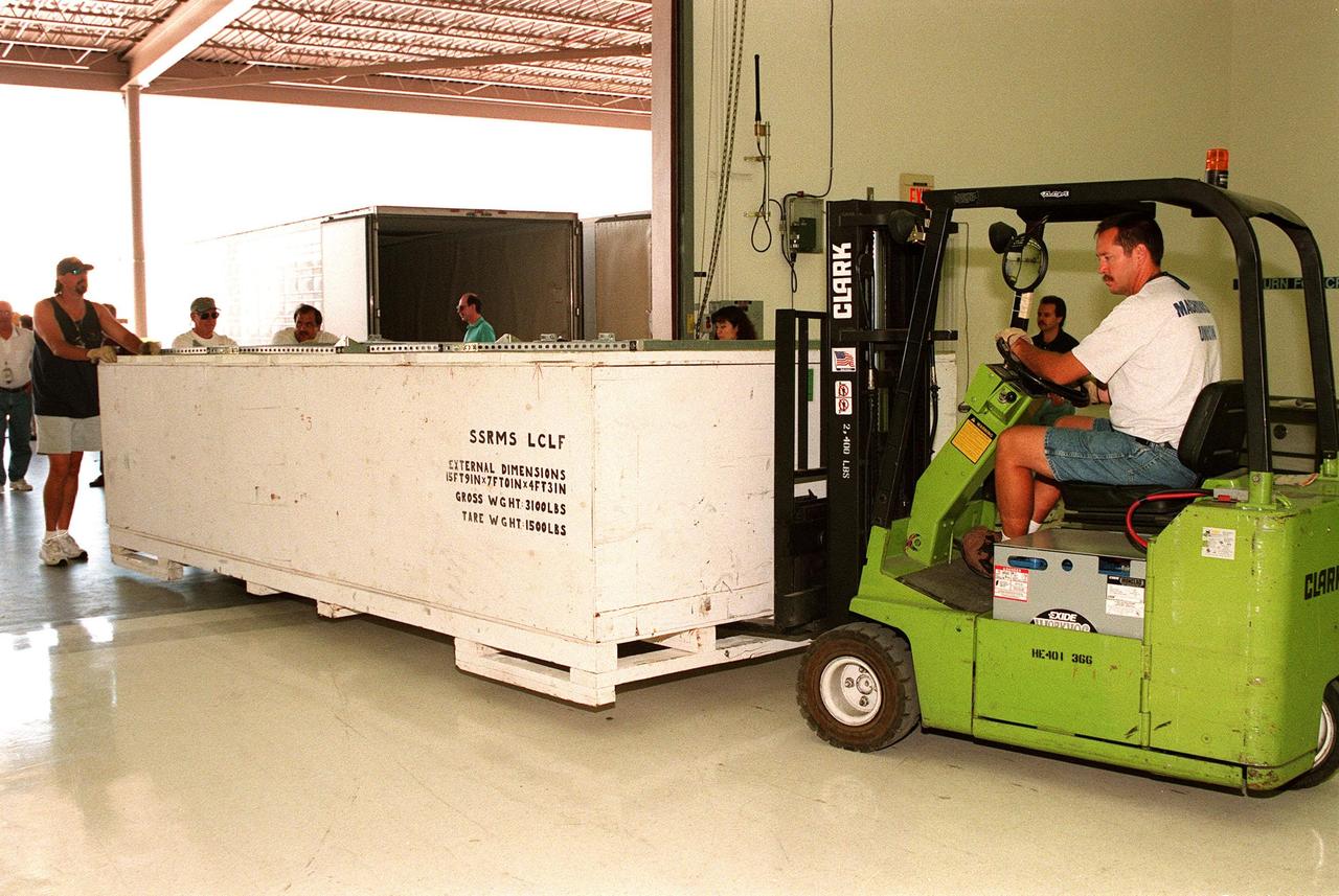 Workers move a box containing a segment of the Canadian Space Agency's (CSA) Space Station Remote Manipulator System (SSRMS) into the Space Station Processing Facility at KSC. It joins two other segments for a campaign of prelaunch processing activities CSA's first contribution to the International Space Station (ISS), the SSRMS is the primary means of transferring payloads between the orbiter payload bay and the ISS for assembly. The 56-foot-long robotic arm includes two 12-foot booms joined by a hinge. Seven joints on the arm allow highly flexible and precise movement. Latching End Effectors are mounted on each end of the arm for grappling. Video cameras mounted on the booms and end effectors will give astronauts maximum visibility for operations and maintenance tasks on the ISS. The SSRMS is scheduled to be launched aboard Space Shuttle Endeavour on STS-100, currently planned for July 2000