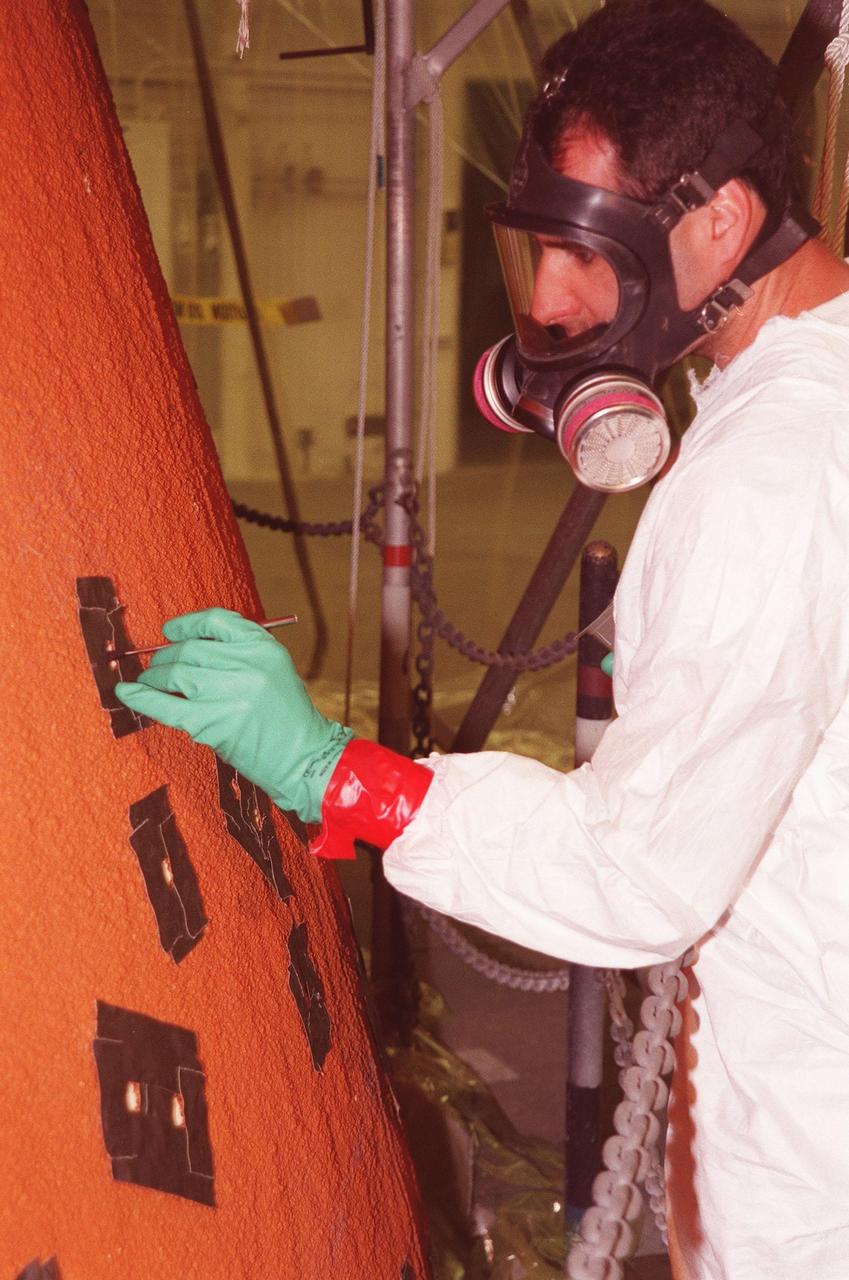 KENNEDY SPACE CENTER, FLA. -- United Space Alliance technician Don Pataky repairs hail-inflicted damage in the foam insulation on the external tank of Space Shuttle Discovery. The Shuttle was rolled back from Pad 39B to the Vehicle Assemby Building for repairs because access to all of the damaged areas was not possible at the pad. The work is expected to take two to three days, allowing Discovery to roll back to the pad late this week for launch of mission STS-96, the 94th launch in the Space Shuttle Program. Liftoff will occur no earlier than May 27. STS-96 is a logistics and resupply mission for the International Space Station, carrying such payloads as a Russian crane, the Strela; a U.S.-built crane; the Spacehab Oceaneering Space System Box (SHOSS), a logistics items carrier; and STARSHINE, a student-shared experiment