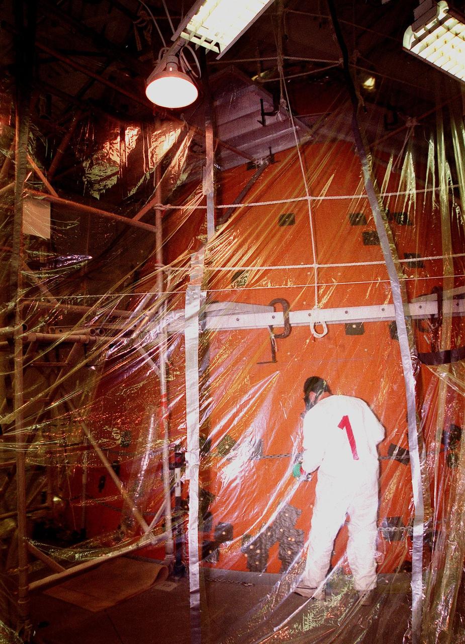 KENNEDY SPACE CENTER, FLA. -- Standing inside a protective tent around the external tank of Space Shuttle Discovery in the Vehicle Assembly Building (VAB), United Space Alliance technician Don Pataky repairs divots caused by hail storms. The Shuttle was rolled back from Pad 39B to the VAB for repairs because access to all of the damaged areas was not possible at the pad. The work is expected to take two to three days, allowing Discovery to roll back to the pad late this week for launch of mission STS-96, the 94th launch in the Space Shuttle Program. Liftoff will occur no earlier than May 27. STS-96 is a logistics and resupply mission for the International Space Station, carrying such payloads as a Russian crane, the Strela; a U.S.-built crane; the Spacehab Oceaneering Space System Box (SHOSS), a logistics items carrier; and STARSHINE, a student-shared experiment