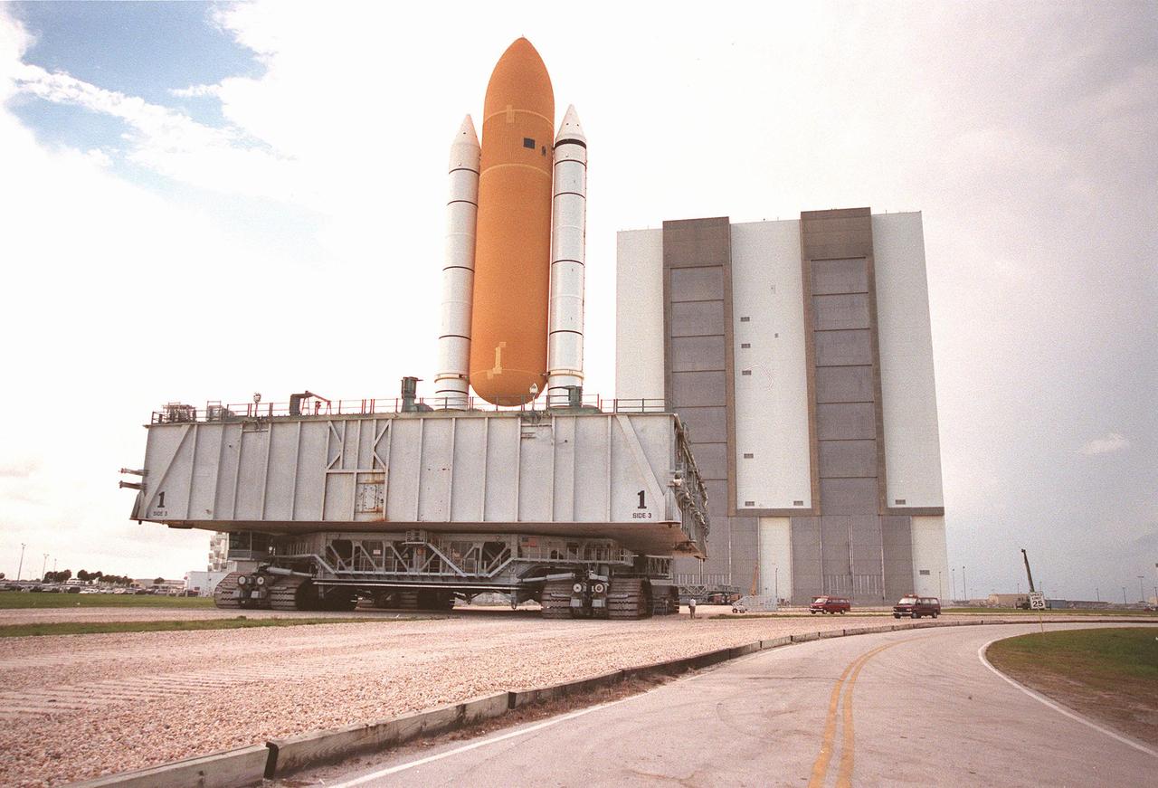 KENNEDY SPACE CENTER, FLA. -- The STS-93 stack of solid rocket boosters and external tank moves toward the Vehicle Assembly Building (VAB) after lightning shield wires were strung from the roof of the VAB for protection. The stack is temporarily being stored outside the VAB while repair work is being done inside on the hail-damaged external tank of Space Shuttle Discovery. Discovery was rolled back from Pad 39B to the VAB for repairs because access to all of the damaged areas was not possible at the pad. The STS-93 stack is expected to be moved back into the VAB after Discovery returns to the pad. The scheduled date for launch of mission STS-96 is no earlier than May 27. STS-93 is targeted for launch on July 22, carrying the Chandra X-ray Observatory