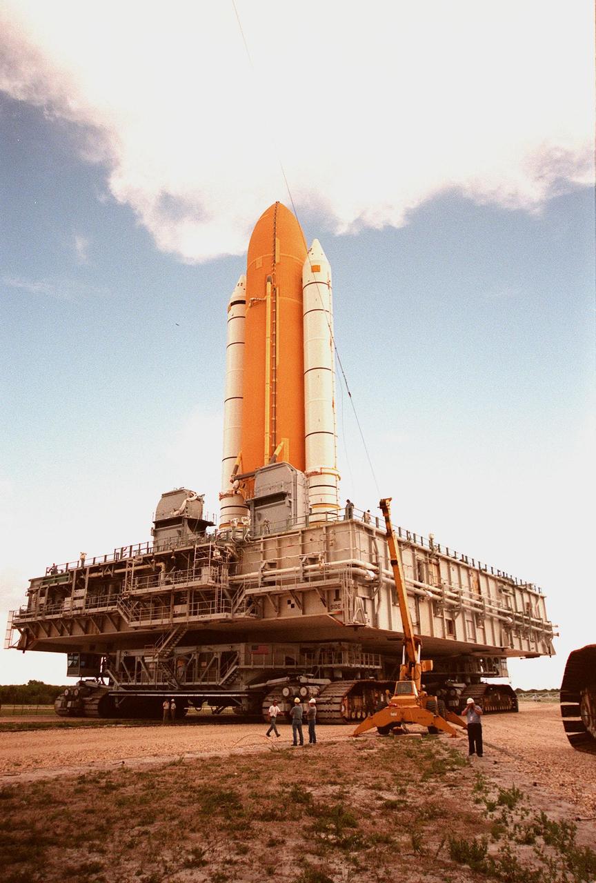 KENNEDY SPACE CENTER, FLA. -- As the STS-93 stack of solid rocket boosters and external tank moves toward the Vehicle Assembly Building (VAB), it passes underneath one of the lightning shield wires strung from the roof of the VAB for protection. The stack is temporarily being stored outside while repair work is being done inside on the hail-damaged external tank of Space Shuttle Discovery. Discovery was rolled back from Pad 39B to the VAB for repairs because access to all of the damaged areas was not possible at the pad. The STS-93 stack is expected to be moved back into the VAB after Discovery returns to the pad. The scheduled date for launch of mission STS-96 is no earlier than May 27. STS-93 is targeted for launch on July 22, carrying the Chandra X-ray Observatory
