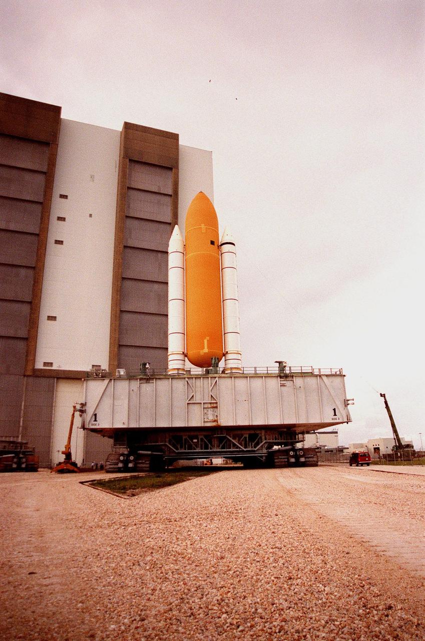 KENNEDY SPACE CENTER, FLA. -- The STS-93 stack of solid rocket boosters and external tank nears the Vehicle Assembly Building (VAB) where it will sit underneath the lightning shield wires strung from the roof of the VAB for protection. The stack is temporarily being stored outside while repair work is being done inside on the hail-damaged external tank of Space Shuttle Discovery. Discovery was rolled back from Pad 39B to the VAB for repairs because access to all of the damaged areas was not possible at the pad. The STS-93 stack is expected to be moved back into the VAB after Discovery returns to the pad. The scheduled date for launch of mission STS-96 is no earlier than May 27. STS-93 is targeted for launch on July 22, carrying the Chandra X-ray Observatory
