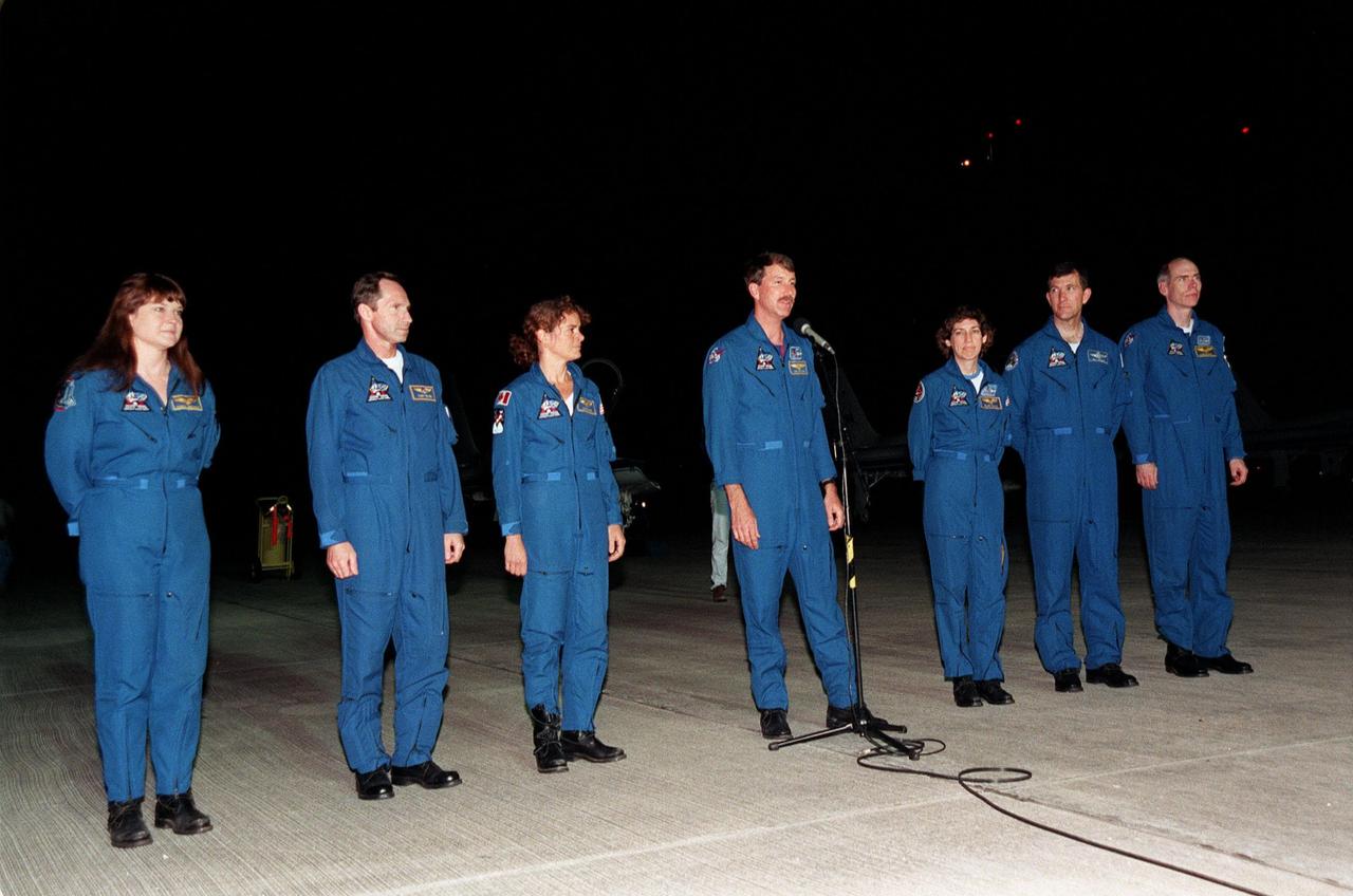 The STS-96 crew talk to the media at KSC's Shuttle Landing Facility after arriving aboard T-38 jet aircraft. From left are Mission Specialists Tamara E. Jernigan, Valery Ivanovich Tokarev and Julie Payette, Commander Kent V. Rominger (at microphone), Mission Specialists Ellen Ochoa, Pilot Rick D. Husband and Daniel T. Barry. The crew will take part in various launch preparations before the scheduled liftoff on May 27 at 6:48 a.m. EDT. STS-96 is a 10-day logistics and resupply mission for the International Space Station, carrying 5000 pounds of supplies to be stored aboard the station for use by future crews, including laptop computers, cameras, tools, spare parts, and clothing. The mission also includes such payloads as a Russian crane, the Strela; a U.S.-built crane; the Spacehab Oceaneering Space System Box (SHOSS), a logistics items carrier; and STARSHINE, a student-involved experiment. The mission will include a space walk to attach the cranes to the outside of the ISS for use in future construction. After the 10-day mission, landing is expected at the SLF on June 6 about 3:25 a.m. EDT