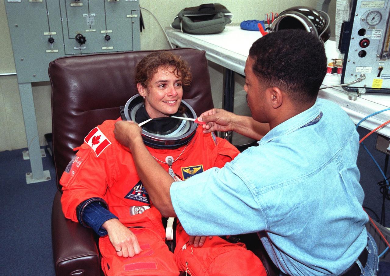 In the Operations and Checkout Building, STS-96 Mission Specialist Julie Payette is assisted by a suit technician in donning her launch and entry suit during final launch preparations. Payette is with the Canadian Space Agency. STS-96 is a 10-day logistics and resupply mission for the International Space Station, carrying about 4,000 pounds of supplies, to be stored aboard the station for use by future crews, including laptop computers, cameras, tools, spare parts, and clothing. The mission also includes such payloads as a Russian crane, the Strela; a U.S.-built crane; the Spacehab Oceaneering Space System Box (SHOSS), a logistics items carrier; and STARSHINE, a student-involved experiment. It will include a space walk to attach the cranes to the outside of the ISS for use in future construction.. Space Shuttle Discovery is due to launch today at 6:49 a.m. EDT. Landing is expected at the SLF on June 6 about 1:58 a.m. EDT