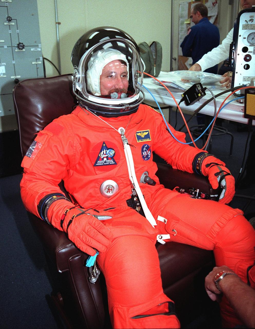 In the Operations and Checkout Building, STS-96 Commander Kent V. Rominger dons his launch and entry suit, plus helmet, during final launch preparations. STS-96 is a 10-day logistics and resupply mission for the International Space Station, carrying about 4,000 pounds of supplies, to be stored aboard the station for use by future crews, including laptop computers, cameras, tools, spare parts, and clothing. The mission also includes such payloads as a Russian crane, the Strela; a U.S.-built crane; the Spacehab Oceaneering Space System Box (SHOSS), a logistics items carrier; and STARSHINE, a student-involved experiment. It will include a space walk to attach the cranes to the outside of the ISS for use in future construction.. Space Shuttle Discovery is due to launch today at 6:49 a.m. EDT. Landing is expected at the SLF on June 6 about 1:58 a.m. EDT