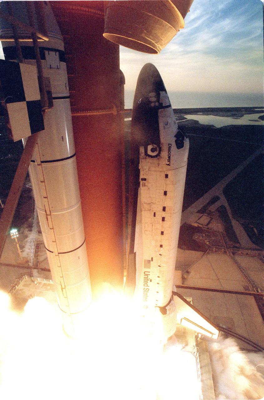 KENNEDY SPACE CENTER, FLA. -- Space Shuttle Discovery begins its climb into space, clearing the fixed service structure at left, after liftoff at 6:49:42 a.m. EDT. The crew of seven begin a 10-day logistics and resupply mission for the International Space Station. Discovery carries about 4,000 pounds of supplies, to be stored aboard the station for use by future crews, including laptop computers, cameras, tools, spare parts, and clothing. The mission also includes such payloads as a Russian crane, the Strela; a U.S.-built crane; the Spacehab Oceaneering Space System Box (SHOSS), a logistics items carrier; and STARSHINE, a student-involved experiment. It will include a space walk to attach the cranes to the outside of the ISS for use in future construction. Landing is expected at the SLF on June 6 about 1:58 a.m. EDT