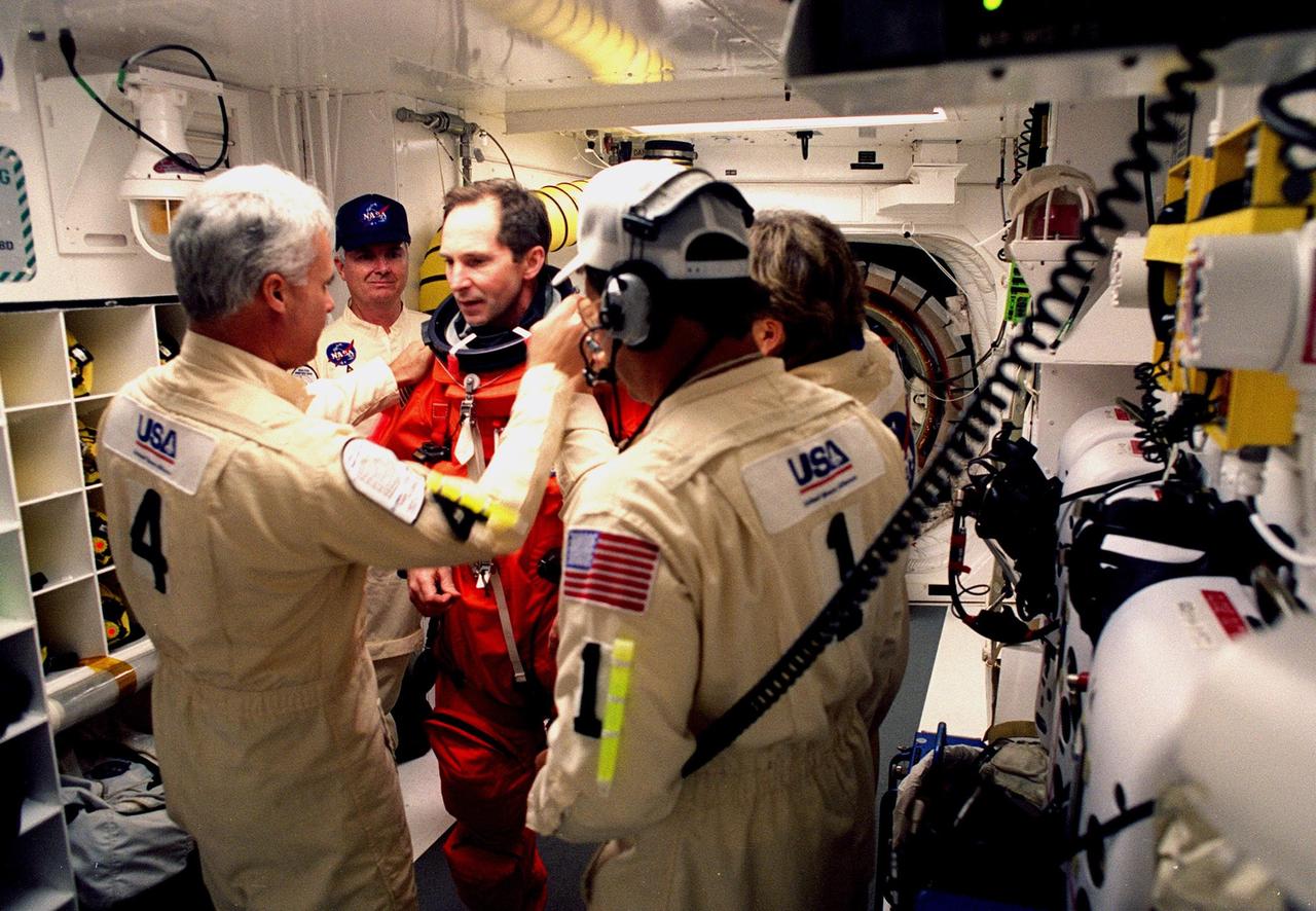 Before entering the orbiter Discovery, STS-96 Mission Specialist Valery Ivanovich Tokarev (center) is checked out by white room closeout crew members Mechanical Technician Chris Meinert and Quality Assurance Specialist Jim Davis on the left, and Closeout Chief Travis Thompson and Suit Technician Jean Alexander on the right. The white room is an environmental chamber at the end of the orbiter access arm that provides entry to the orbiter crew compartment. STS-96 is a 10-day logistics and resupply mission for the International Space Station, carrying about 4,000 pounds of supplies, to be stored aboard the station for use by future crews, including laptop computers, cameras, tools, spare parts, and clothing. The mission also includes such payloads as a Russian crane, the Strela; a U.S.-built crane; the Spacehab Oceaneering Space System Box (SHOSS), a logistics items carrier; and STARSHINE, a student-involved experiment. It will include a space walk to attach the cranes to the outside of the ISS for use in future construction. Space Shuttle Discovery is due to launch today at 6:49 a.m. EDT. Landing is expected at the SLF on June 6 about 1:58 a.m. EDT