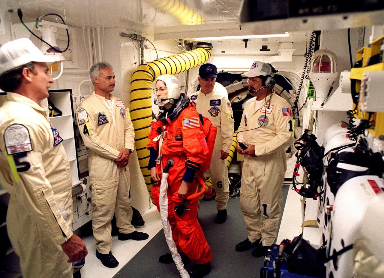 STS-96 Mission Specialist Ellen Ochoa chats with white room closeout crew members while being checked out for entry into the orbiter Discovery. At left are Mechanical Technicians Al Schmidt and Chris meinert; at right is Quality Assurance Specialist James Davis and Closeout Chief Travis Thompson. The white room is an environmental chamber at the end of the orbiter access arm that provides entry to the orbiter crew compartment. STS-96 is a 10-day logistics and resupply mission for the International Space Station, carrying about 4,000 pounds of supplies, to be stored aboard the station for use by future crews, including laptop computers, cameras, tools, spare parts, and clothing. The mission also includes such payloads as a Russian crane, the Strela; a U.S.-built crane; the Spacehab Oceaneering Space System Box (SHOSS), a logistics items carrier; and STARSHINE, a student-involved experiment. It will include a space walk to attach the cranes to the outside of the ISS for use in future construction. Space Shuttle Discovery is due to launch today at 6:49 a.m. EDT. Landing is expected at the SLF on June 6 about 1:58 a.m. EDT