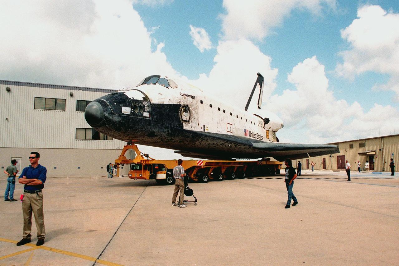KENNEDY SPACE CENTER, FLA. -- The orbiter Columbia, aboard its orbiter transporter system, makes the turn from the Orbiter Processing Facility (behind it, left) to the nearby Vehicle Assembly Building (VAB) for external tank mating operations. Columbia is scheduled for rollout to Launch Pad 39B on Monday, June 7, for mission STS-93. The primary mission objective will be the deployment of the Advanced X-ray Astrophysics Facility, recently renamed the Chandra X-Ray Observatory. Mission STS-93 will be the first Space Shuttle commanded by a woman, Commander Eileen M. Collins. It is scheduled to launch July 22 at 12:27 a.m. EDT although that date is currently under review