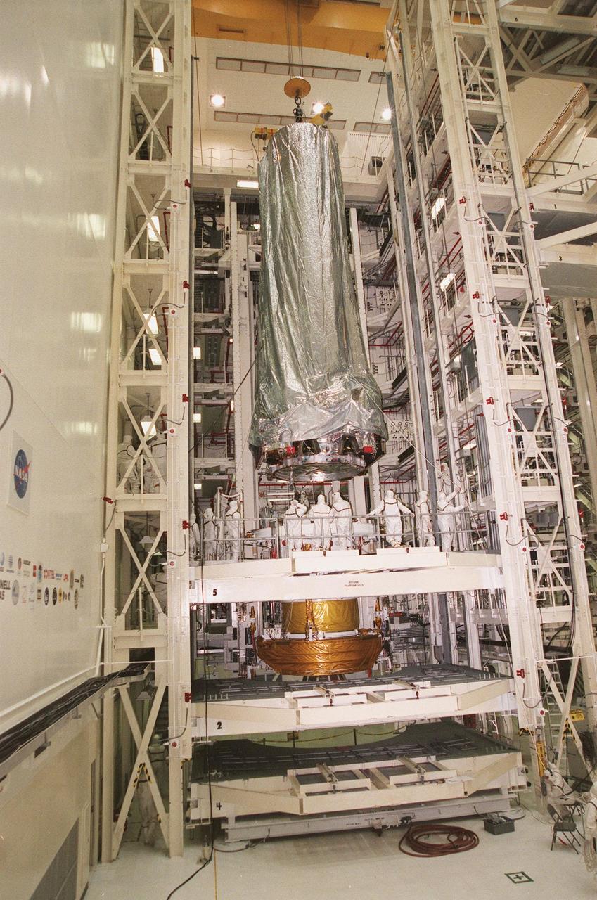 In the Vertical Processing Facility, the Chandra X-ray Observatory is lowered toward the Inertial Upper Stage (IUS) in a workstand beneath it. There it will be mated with the IUS and then undergo testing to validate the IUS/Chandra connections and to check the orbiter avionics interfaces. Following that, an end-to-end test (ETE) will be conducted to verify the communications path to Chandra, commanding it as if it were in space. With the world's most powerful X-ray telescope, Chandra will allow scientists from around the world to see previously invisible black holes and high-temperature gas clouds, giving the observatory the potential to rewrite the books on the structure and evolution of our universe. Chandra is scheduled for launch July 22 aboard Space Shuttle Columbia, on mission STS-93