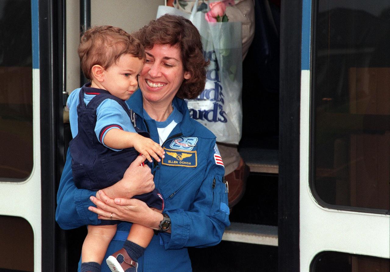 STS-96 Mission Specialist Ellen Ochoa (Ph.D.), holding her son, Wilson Miles-Ochoa , leaves the bus at the Cape Canaveral Air Station Skid Strip. The STS-96 crew members are preparing to return to the Johnson Space Center in Houston, Texas, after a successful 10-day mission to the International Space Station aboard Space Shuttle Discovery. The crew landed June 6 at 2:02:43 a.m. EDT, in the 11th night landing at KSC. Other crew members also returning are Commander Kent V. Rominger, Pilot Rick D. Husband, and Mission Specialists Tamara Jernigan (Ph.D.), Daniel Barry (M.D., Ph.D.), Julie Payette (with the Canadian Space Agency) and Valery Ivanovich Tokarev (with the Russian Space Agency)