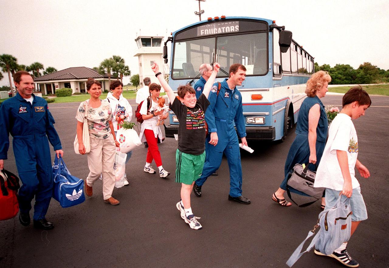 STS-96 crew members and their families exit the bus at the Cape Canaveral Air Station Skid Strip to return to the Johnson Space Center in Houston, Texas. From left are Mission Specialist Valery Ivanovich Tokarev (with the Russian Space Agency) and his wife, Irina; Sue Barry and Jennifer Barry, the wife and daughter, respectively, of Mission Specialist Daniel Barry (M.D., Ph.D.) (background); (foreground) Andrew Barry, son of Daniel; Pilot Rick D. Husband and his wife, Evelyn; and Ivan Tokarev, son of Valery. Other crew members also returning are Commander Kent V. Rominger and Mission Specialists Ellen Ochoa (Ph.D.), Tamara E. Jernigan (Ph.D.), and Julie Payette (with the Canadian Space Agency). After a successful 10-day mission to the International Space Station aboard Space Shuttle Discovery, the crew landed June 6 at 2:02:43 a.m. EDT, in the 11th night landing at KSC