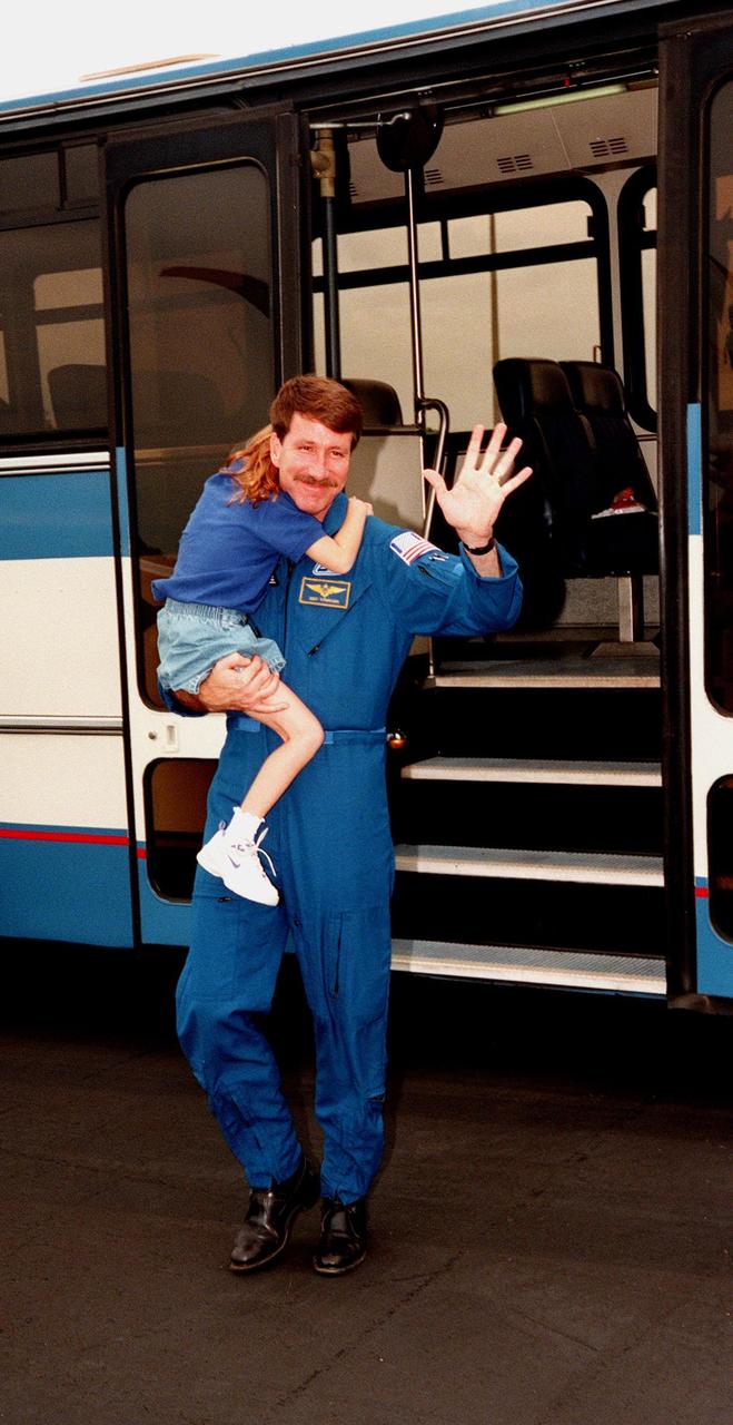 STS-96 Commander Kent V. Rominger, holding his daughter, Kristen, exits the bus at the Cape Canaveral Air Station Skid Strip before boarding a plane for a return to the Johnson Space Center in Houston, Texas. Other crew members also returning are Pilot Rick D. Husband, and Mission Specialists Ellen Ochoa (Ph.D.), Tamara E. Jernigan (Ph.D.), Daniel T. Barry (M.D., Ph.D.), Julie Payette, with the Canadian Space Agency, and Valery Ivanovich Tokarev, with the Russian Space Agency. After a successful 10-day mission to the International Space Station aboard Space Shuttle Discovery, the STS-96 crew landed June 6 at 2:02:43 a.m. EDT, in the 11th night landing at KSC