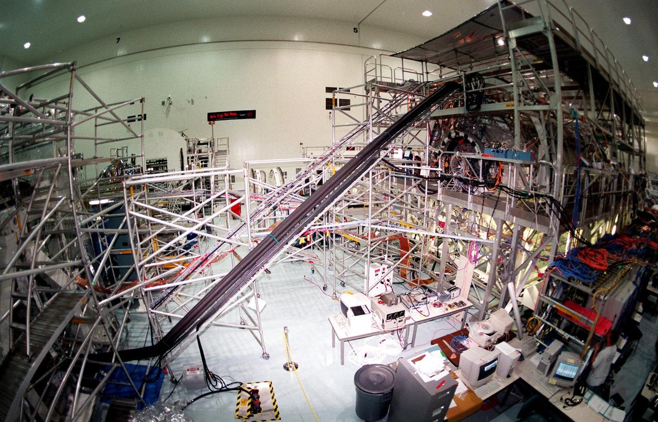 In The Space Station Processing Facility, a Multi-Element Integration Test (MEIT) is underway to ensure components of the International Space Station work together before they are launched into orbit. Within the framework at right is the U.S. Lab, called Destiny; at left is the Z-1 truss. The current MEIT combines the P-6 photovoltaic module, the Z-1 truss and the Pressurized Mating Adapter 3. Electrical and fluid connections are being hooked up to verify how the ISS elements operate together