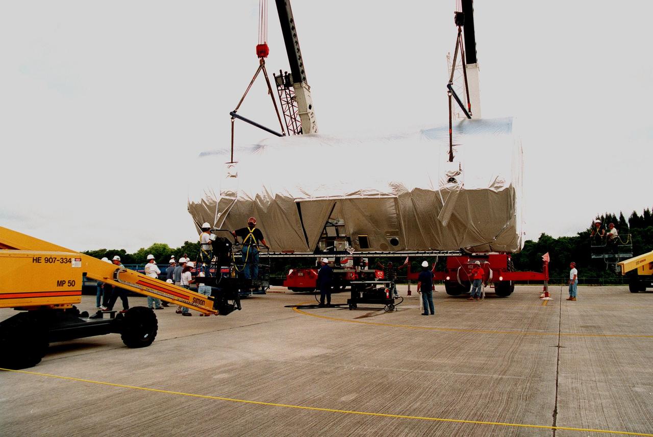 KENNEDY SPACE CENTER, FLA. -- At KSC's Shuttle Landing Facility, workers load the S0 truss segment onto a flatbed trailer for its transfer to the Operations and Checkout Bldg. for processing. The truss arrived at the SLF aboard a "Super Guppy" aircraft from Boeing in Huntington, Calif. During processing in the O&C, the S0 truss will have installed the Canadian Mobile Transporter, power distribution system modules, a heat pipe radiator for cooling, computers, and a pair of rate gyroscopes. Four Global Positioning System antennas are already installed. A 44by 15-foot structure weighing 30,800 pounds when fully outfitted and ready for launch, the truss will be at the center of the ISS 10-truss, girderlike structure that will ultimately extend the length of a football field. Eventually the S0 truss will be attached to the U.S. Lab, "Destiny," which is scheduled to be added to the ISS in April 2000. Later, other trusses will be attached to the S0 on-orbit. The S0 truss is scheduled to be launched in the first quarter of 2001 on mission STS-108
