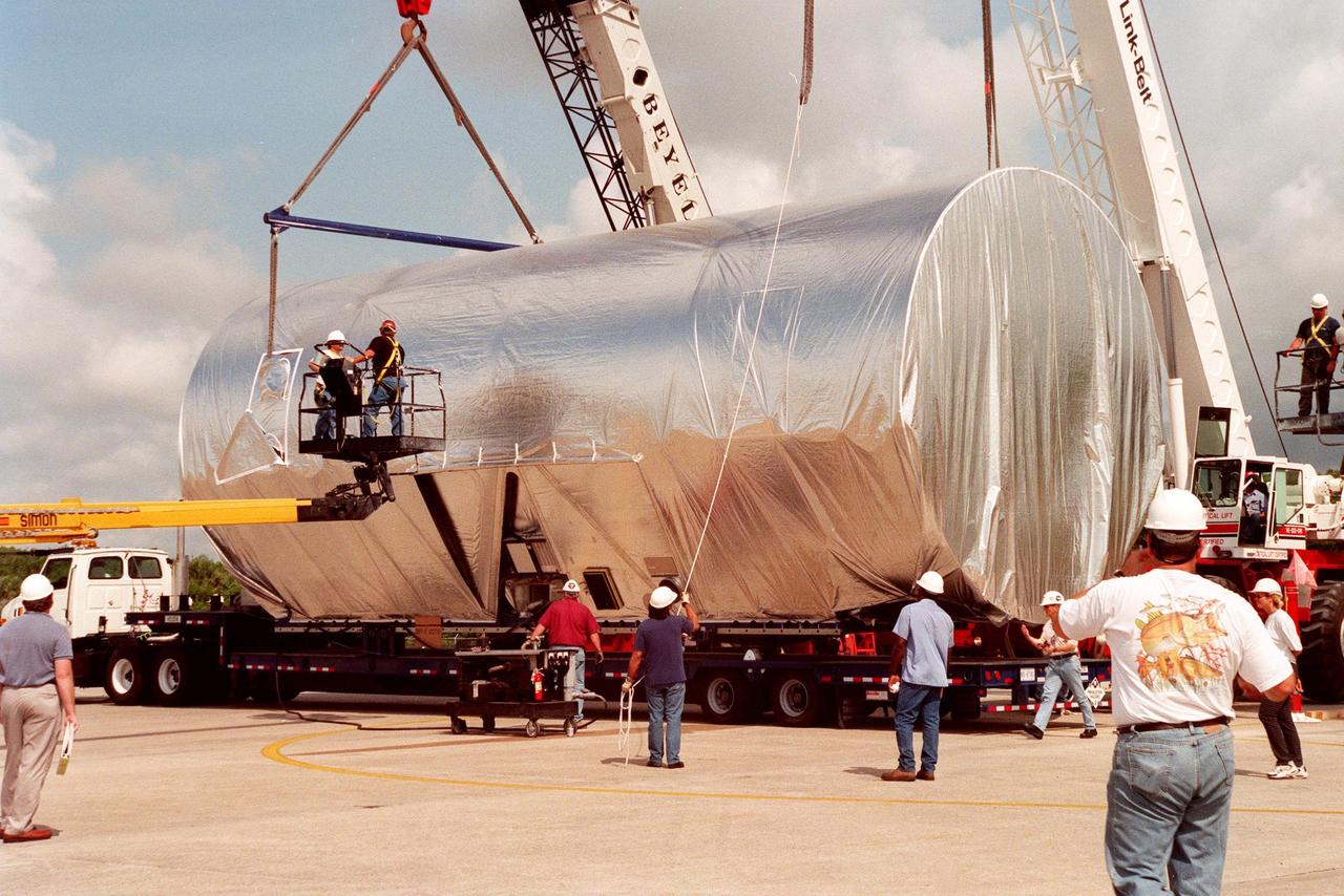 KENNEDY SPACE CENTER, FLA. -- At KSC's Shuttle Landing Facility, workers finish loading the S0 truss segment onto a flatbed trailer for transfer to the Operations and Checkout Bldg. for processing. The truss arrived at the SLF aboard a "Super Guppy" aircraft from Boeing in Huntington, Calif. During processing in the O&C, the S0 truss will have installed the Canadian Mobile Transporter, power distribution system modules, a heat pipe radiator for cooling, computers, and a pair of rate gyroscopes. Four Global Positioning System antennas are already installed. A 44by 15-foot structure weighing 30,800 pounds when fully outfitted and ready for launch, the truss will be at the center of the ISS 10-truss, girderlike structure that will ultimately extend the length of a football field. Eventually the S0 truss will be attached to the U.S. Lab, "Destiny," which is scheduled to be added to the ISS in April 2000. Later, other trusses will be attached to the S0 on-orbit. The S0 truss is scheduled to be launched in the first quarter of 2001 on mission STS-108