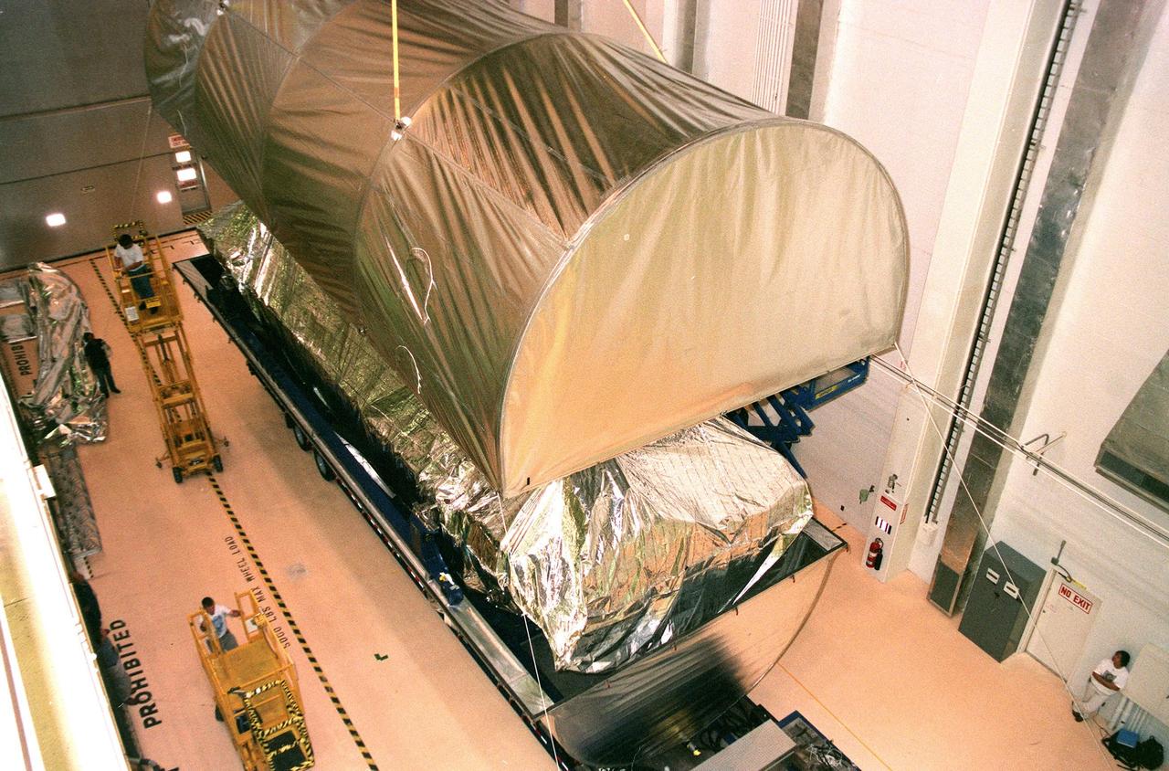 KENNEDY SPACE CENTER, FLA. -- Inside the Operations and Checkout Bldg. (O&C), an overhead crane removes the cover from the S0 truss segment beneath it. The S0 truss will undergo processing in the O&C during which the Canadian Mobile Transporter, power distribution system modules, a heat pipe radiator for cooling, computers, and a pair of rate gyroscopes will be installed. Four Global Positioning System antennas are already installed. A 44by 15-foot structure weighing 30,800 pounds when fully outfitted and ready for launch, the truss will be at the center of the ISS 10-truss, girderlike structure that will ultimately extend the length of a football field. Eventually the S0 truss will be attached to the U.S. Lab, "Destiny," which is scheduled to be added to the ISS in April 2000. Later, other trusses will be attached to the S0 on-orbit. The S0 truss is scheduled to be launched in the first quarter of 2001 on mission STS-108