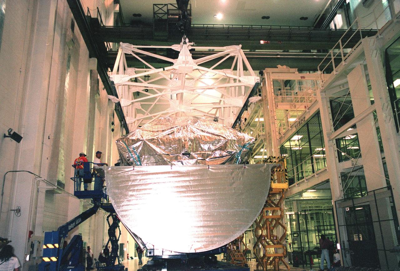 KENNEDY SPACE CENTER, FLA. -- Inside the Operations and Checkout Bldg. (O&C), workers (at left) watch over the maneuvering of the overhead crane toward the S0 truss segment below it. The S0 truss will undergo processing in the O&C during which the Canadian Mobile Transporter, power distribution system modules, a heat pipe radiator for cooling, computers, and a pair of rate gyroscopes will be installed. Four Global Positioning System antennas are already installed. A 44by 15-foot structure weighing 30,800 pounds when fully outfitted and ready for launch, the truss will be at the center of the ISS 10-truss, girderlike structure that will ultimately extend the length of a football field. Eventually the S0 truss will be attached to the U.S. Lab, "Destiny," which is scheduled to be added to the ISS in April 2000. Later, other trusses will be attached to the S0 on-orbit. The S0 truss is scheduled to be launched in the first quarter of 2001 on mission STS-108