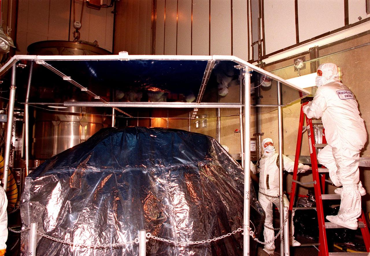 At Launch Pad 17A, Cape Canaveral Air Station (CCAS), workers check out the protective cover placed over the top of NASA's Far Ultraviolet Spectroscopic Explorer (FUSE) satellite. The satellite is scheduled to be launched from CCAS June 23 aboard a Boeing Delta II rocket. FUSE is designed to scour the cosmos for the fossil record of the origins of the universe hydrogen and deuterium. Scientists will use FUSE to study hydrogen and deuterium to unlock the secrets of how the primordial chemical elements of which all stars, planets and life evolved, were created and distributed since the birth of the universe