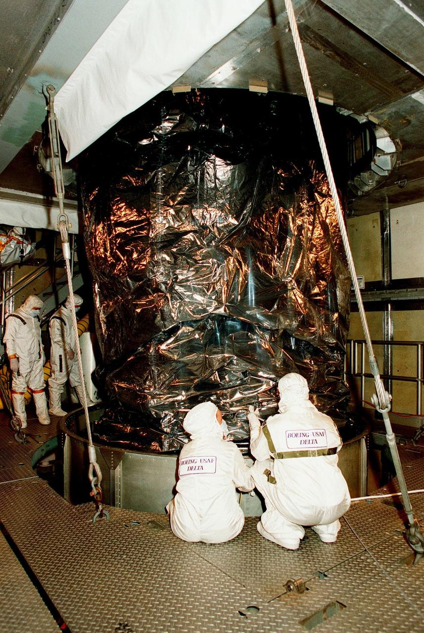 At Launch Pad 17A, Cape Canaveral Air Station (CCAS), workers look over NASA's Far Ultraviolet Spectroscopic Explorer (FUSE) satellite after sections of the canister have been removed. FUSE is scheduled to be launched from CCAS June 23 aboard a Boeing Delta II rocket. FUSE is designed to scour the cosmos for the fossil record of the origins of the universe hydrogen and deuterium. Scientists will use FUSE to study hydrogen and deuterium to unlock the secrets of how the primordial chemical elements of which all stars, planets and life evolved, were created and distributed since the birth of the universe