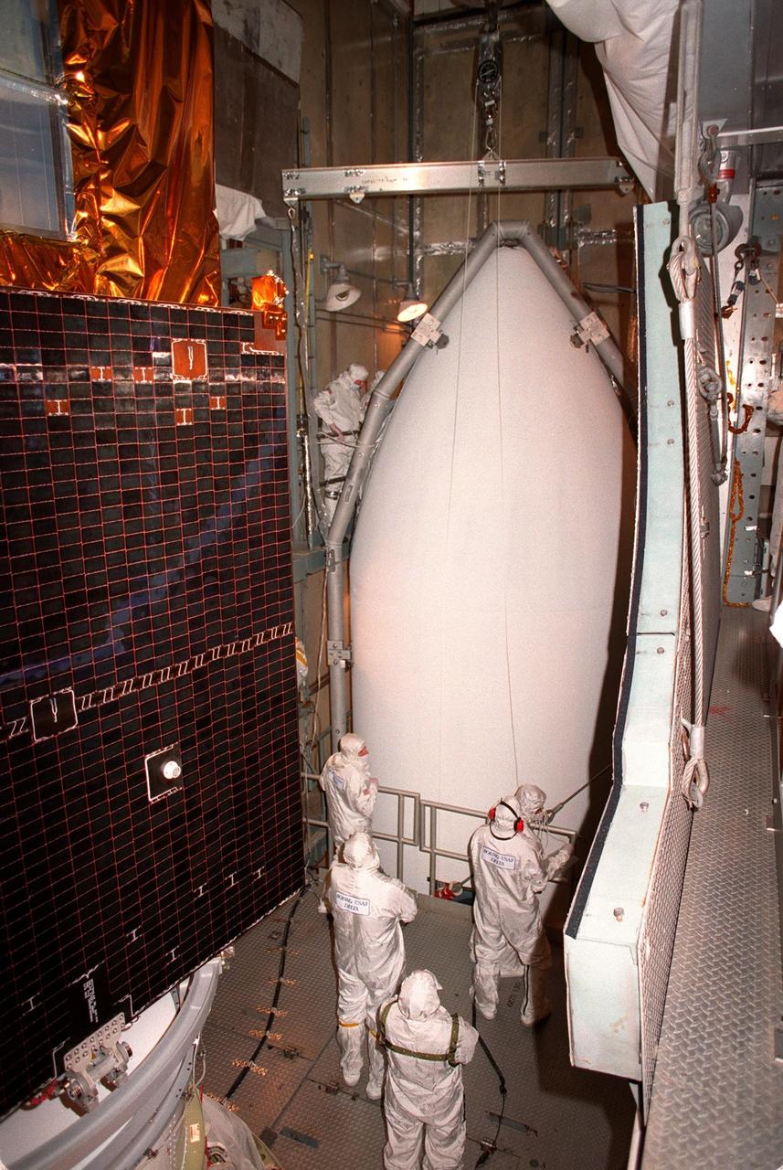 At Launch Pad 17A, Cape Canaveral Air Station, workers oversee the lifting of the fairing (right) into the tower. At left is NASA's Far Ultraviolet Spectroscopic Explorer (FUSE) satellite around which the fairing will be fitted. The satellite is scheduled for launch June 24 aboard a Boeing Delta II rocket. FUSE is designed to scour the cosmos for the fossil record of the origins of the universe hydrogen and deuterium. Scientists will use FUSE to study hydrogen and deuterium to unlock the secrets of how the primordial chemical elements of which all stars, planets and life evolved, were created and distributed since the birth of the universe