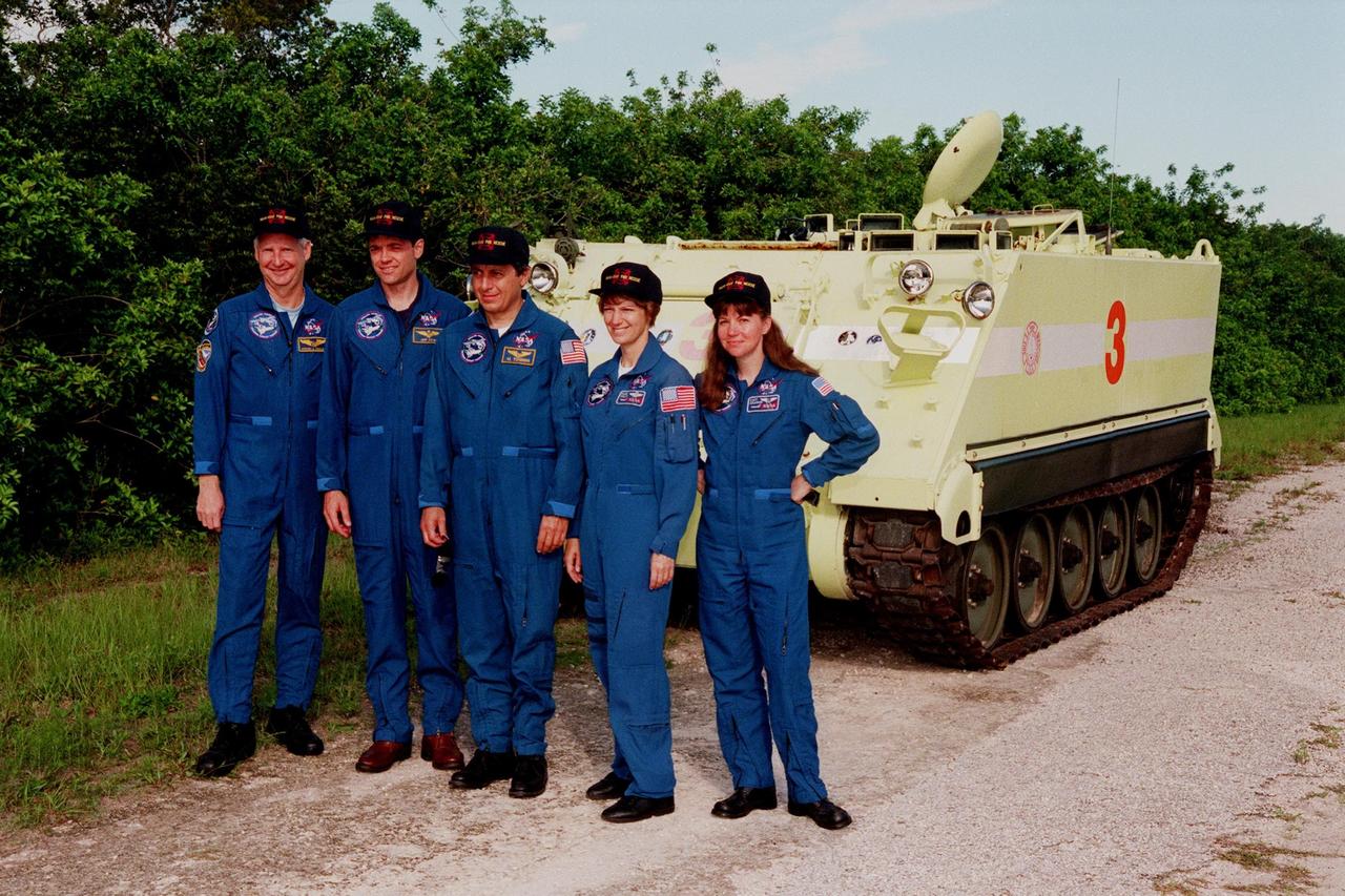 The STS-93 crew pose in front of an M-113, an armored personnel carrier, which they will use for emergency egress training from the launch pad. From left are Mission Specialist Steven A. Hawley (Ph.D.), Pilot Jeffrey S. Ashby, Mission Specialist Michel Tognini of France, Commander Eileen M. Collins and Mission Specialist Catherine G. Coleman (Ph.D.). Collins is the first woman to serve as mission commander. Tognini represents the Centre National d'Etudes Spatiales (CNES). TCDT activities familiarize the crew with the mission, provide training in emergency exit from the orbiter and launch pad, and include a launch-day dress rehearsal culminating with a simulated main engine cut-off. The primary mission of STS-93 is the release of the Chandra X-ray Observatory, which will allow scientists from around the world to obtain unprecedented X-ray images of exotic environments in space to help understand the structure and evolution of the universe. Chandra is expected to provide unique and crucial information on the nature of objects ranging from comets in our solar system to quasars at the edge of the observable universe. Since X-rays are absorbed by the Earth's atmosphere, space-based observatories are necessary to study these phenomena and allow scientists to analyze some of the greatest mysteries of the universe. The targeted launch date for STS-93 is no earlier than July 20 at 12:36 a.m. EDT from Launch Pad 39B