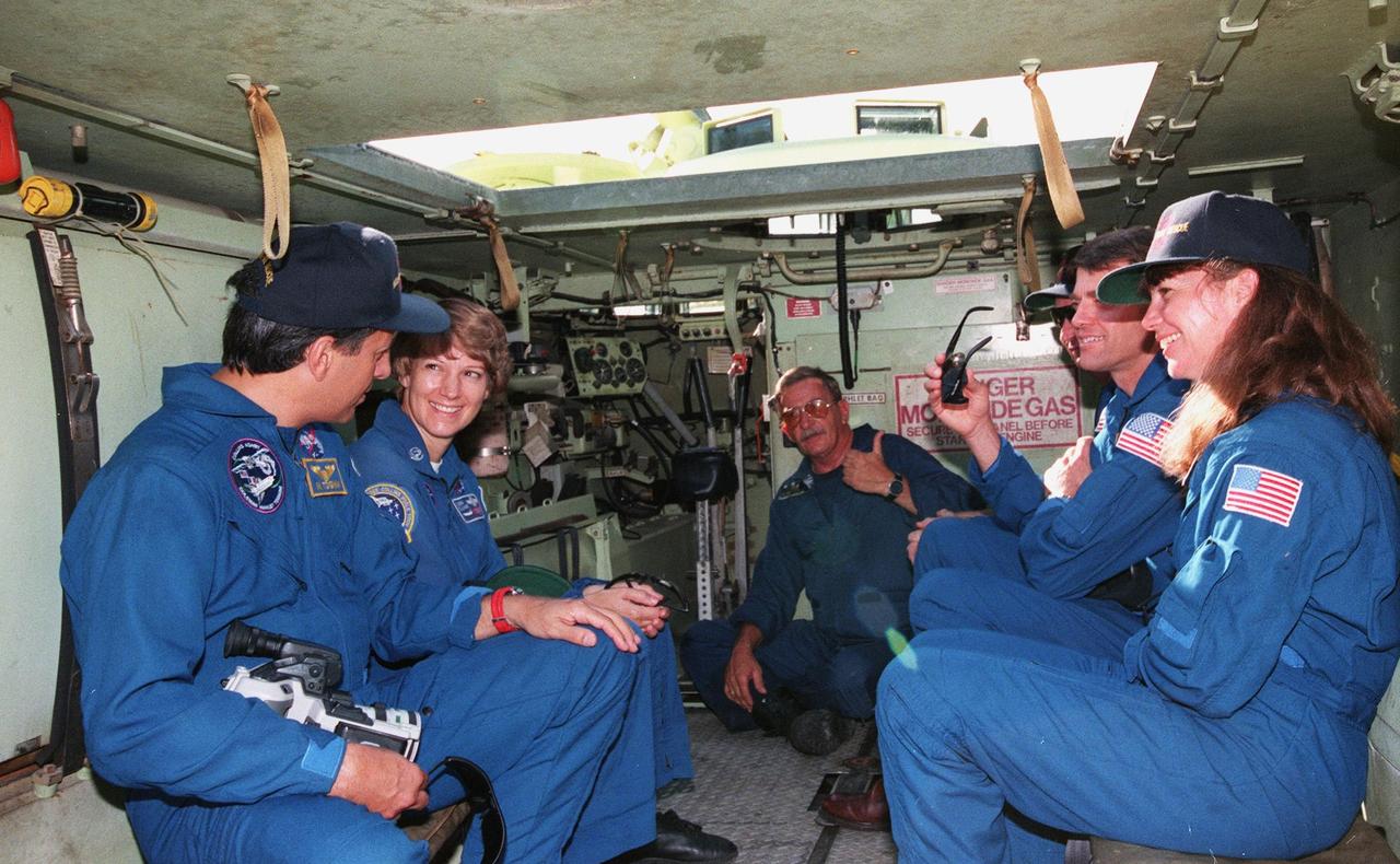 Inside an M-113 armored personnel carrier at the launch pad, the STS-93 crew take part in emergency egress training under the watchful eyes of Capt. George Hoggard (center), trainer with the KSC Fire Department. From left are Mission Specialist Michel Tognini of France, Commander Eileen M. Collins, Hoggard, Mission Specialist Steven A. Hawley (Ph.D.), Pilot Jeffrey S. Ashby, and Mission Specialist Catherine G. Coleman (Ph.D.). Collins is the first woman to serve as mission commander. Tognini represents the Centre National d'Etudes Spatiales (CNES). The training is part of Terminal Countdown Demonstration Test activities that also include a launch-day dress rehearsal culminating with a simulated main engine cut-off. The primary mission of STS-93 is the release of the Chandra X-ray Observatory, which will allow scientists from around the world to obtain unprecedented X-ray images of exotic environments in space to help understand the structure and evolution of the universe. Chandra is expected to provide unique and crucial information on the nature of objects ranging from comets in our solar system to quasars at the edge of the observable universe. Since X-rays are absorbed by the Earth's atmosphere, space-based observatories are necessary to study these phenomena and allow scientists to analyze some of the greatest mysteries of the universe. The targeted launch date for STS-93 is no earlier than July 20 at 12:36 a.m. EDT from Launch Pad 39B