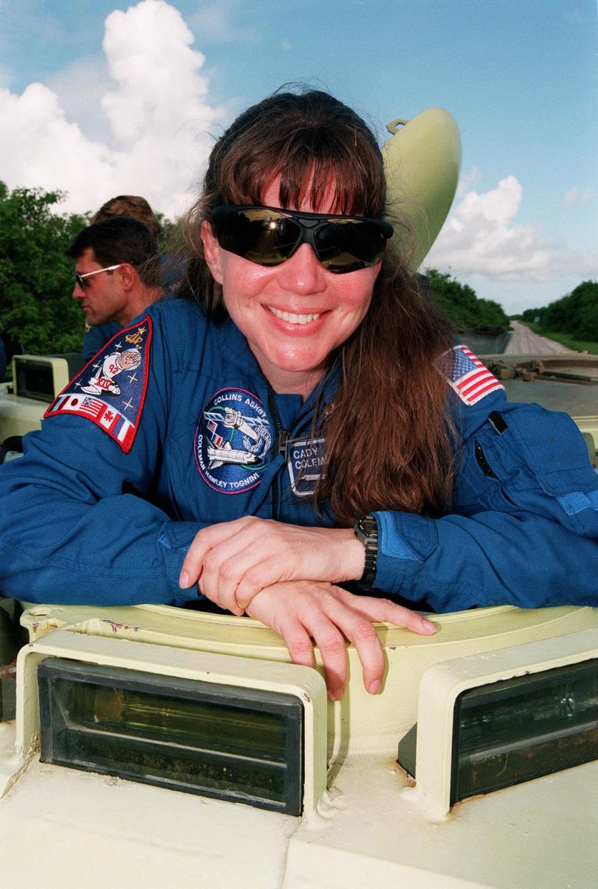 STS-93 Mission Specialist Catherine G. Coleman (Ph.D.) smiles for the photographer before climbing into an M-113 armored personnel carrier at the launch pad to take part in emergency egress training. In preparation for their mission, the STS-93 crew are participating in Terminal Countdown Demonstration Test activities that also include a launch-day dress rehearsal culminating with a simulated main engine cut-off. Others in the crew are Commander Eileen M. Collins, Pilot Jeffrey S. Ashby, and Mission Specialists Steven A. Hawley (Ph.D.) and Michel Tognini of France, who represents the Centre National d'Etudes Spatiales (CNES). Collins is the first woman to serve as a mission commander. The primary mission of STS-93 is the release of the Chandra X-ray Observatory, which will allow scientists from around the world to obtain unprecedented X-ray images of exotic environments in space to help understand the structure and evolution of the universe. Chandra is expected to provide unique and crucial information on the nature of objects ranging from comets in our solar system to quasars at the edge of the observable universe. Since X-rays are absorbed by the Earth's atmosphere, space-based observatories are necessary to study these phenomena and allow scientists to analyze some of the greatest mysteries of the universe. The targeted launch date for STS-93 is no earlier than July 20 at 12:36 a.m. EDT from Launch Pad 39B