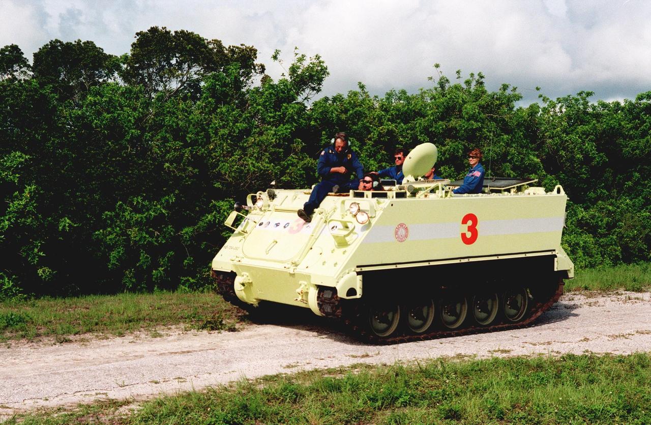 Under the watchful eyes of Capt. George Hoggard (left), trainer with the KSC Fire Department, STS-93 Mission Specialist Catherine G. Coleman (Ph.D.) drives the M-113 armored personnel carrier during emergency egress training at the launch pad. Behind her is Pilot Jeffrey S. Ashby and Commander Eileen M. Collins. In preparation for their mission, the STS-93 crew are participating in Terminal Countdown Demonstration Test activities that also include a launch-day dress rehearsal culminating with a simulated main engine cut-off. Others in the crew participating are Mission Specialists Steven A. Hawley (Ph.D.) and Michel Tognini of France, who represents the Centre National d'Etudes Spatiales (CNES). Collins is the first woman to serve as a mission commander. The primary mission of STS-93 is the release of the Chandra X-ray Observatory, which will allow scientists from around the world to obtain unprecedented X-ray images of exotic environments in space to help understand the structure and evolution of the universe. Chandra is expected to provide unique and crucial information on the nature of objects ranging from comets in our solar system to quasars at the edge of the observable universe. Since X-rays are absorbed by the Earth's atmosphere, space-based observatories are necessary to study these phenomena and allow scientists to analyze some of the greatest mysteries of the universe. The targeted launch date for STS-93 is no earlier than July 20 at 12:36 a.m. EDT from Launch Pad 39B