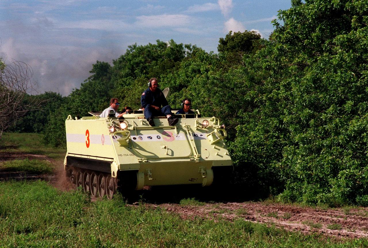 Under the watchful eyes of KSC Fire Department trainer Capt. George Hoggard (seated on the front), STS-93 Mission Specialist Michel Tognini of France (right) drives the M-113 armored personnel carrier during emergency egress training at the launch pad. Tognini represents the Centre National d'Etudes Spatiales (CNES). At the far left is Roland Nedelkovich, with the Vehicle Integration Test Team, JSC. In preparation for their mission, the STS-93 crew are participating in Terminal Countdown Demonstration Test activities that also include a launch-day dress rehearsal culminating with a simulated main engine cut-off. Others in the crew participating are Commander Eileen M. Collins, Pilot Jeffrey S. Ashby, and Mission Specialists Steven A. Hawley (Ph.D.) and Catherine G. Coleman (Ph.D.) Collins is the first woman to serve as a Shuttle commander. The primary mission of STS-93 is the release of the Chandra X-ray Observatory, which will allow scientists from around the world to obtain unprecedented X-ray images of exotic environments in space to help understand the structure and evolution of the universe. Chandra is expected to provide unique and crucial information on the nature of objects ranging from comets in our solar system to quasars at the edge of the observable universe. Since X-rays are absorbed by the Earth's atmosphere, space-based observatories are necessary to study these phenomena and allow scientists to analyze some of the greatest mysteries of the universe. The targeted launch date for STS-93 is no earlier than July 20 at 12:36 a.m. EDT from Launch Pad 39B
