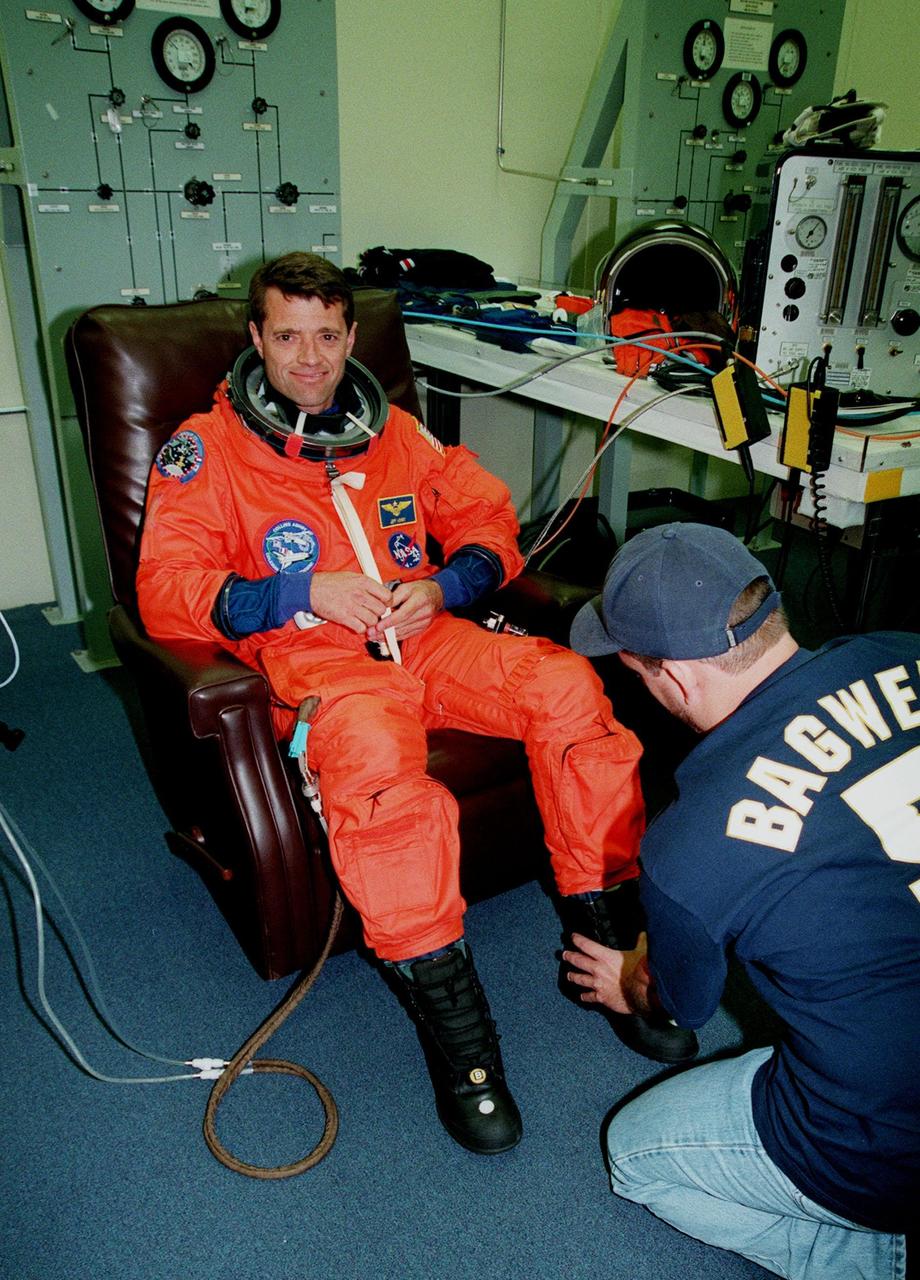 STS-93 Pilot Jeffrey S. Ashby has his launch and entry suit checked by a technician in the Operations and Checkout Bldg. In preparation for their mission, the STS-93 crew are participating in Terminal Countdown Demonstration Test activities that also include equipment check and a launch-day dress rehearsal culminating with a simulated main engine cut-off. Others in the crew participating are Commander Eileen M. Collins and Mission Specialists Steven A. Hawley (Ph.D.), Catherine G. Coleman (Ph.D.) and Michel Tognini of France, who represents the Centre National d'Etudes Spatiales (CNES). Collins is the first woman to serve as a Shuttle commander. The primary mission of STS-93 is the release of the Chandra X-ray Observatory, which will allow scientists from around the world to obtain unprecedented X-ray images of exotic environments in space to help understand the structure and evolution of the universe. The targeted launch date for STS-93 is no earlier than July 20 at 12:36 a.m. EDT from Launch Pad 39B