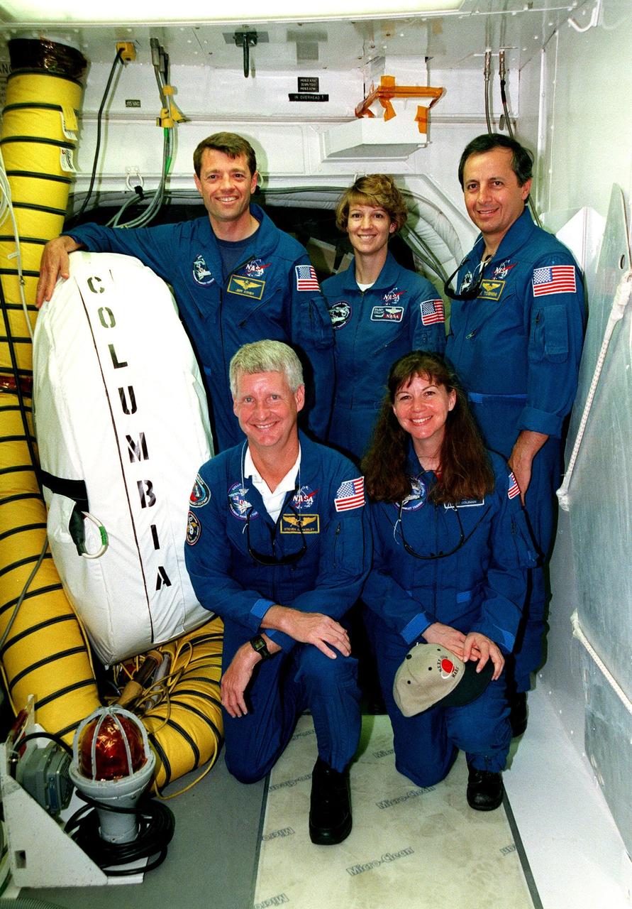 KENNEDY SPACE CENTER, FLA. -- Inside the "White Room" at Launch Pad 39B, the STS-93 crew poses for a photo before passing through the hatch on the orbiter Columbia. In the back row are Pilot Jeffrey S. Ashby, Commander Eileen M. Collins and Mission Specialist Michel Tognini of France, who represents the Centre National d'Etudes Spatiales (CNES). Kneeling in front are Mission Specialists Steven A. Hawley (Ph.D.), and Catherine G. Coleman (Ph.D.). The White Room is an environmentally controlled chamber that abuts the orbiter hatch. In preparation for their mission, the STS-93 crew members are participating in a Terminal Countdown Demonstration Test, which familiarizes them with the mission, provides training in emergency exit from the orbiter and launch pad, and includes a launch-day dress rehearsal culminating with a simulated main engine cut-off. The primary mission of STS-93 is the release of the Chandra X-ray Observatory, which will allow scientists from around the world to obtain unprecedented X-ray images of exotic environments in space to help understand the structure and evolution of the universe. The targeted launch date for STS-93 is no earlier than July 20 at 12:36 a.m. EDT from Launch Pad 39B