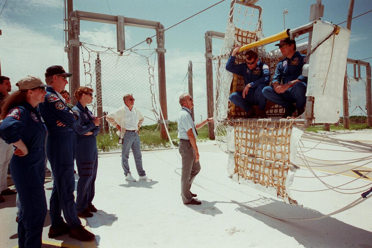 (From left) STS-93 Mission Specialists Catherine G. Coleman (Ph.D.) and Steven A. Hawley (Ph.D.), and Commander Eileen M. Collins watch and listen to Bob Parks, a Safety Egress trainer with United Space Alliance, explaining the use of the slideware basket for emergency egress from the pad. Inside the basket are Pilot Jeffrey S. Ashby and Mission Specialist Michel Tognini of France, who represents the Centre National d'Etudes Spatiales (CNES). The STS-93 crew members are at KSC to participate in a Terminal Countdown Demonstration Test, which familiarizes them with the mission, provides training in emergency exit from the orbiter and launch pad, and includes a launch-day dress rehearsal culminating with a simulated main engine cut-off. The primary mission of STS-93 is the release of the Chandra X-ray Observatory, which will allow scientists from around the world to obtain unprecedented X-ray images of exotic environments in space to help understand the structure and evolution of the universe. The targeted launch date for STS-93 is no earlier than July 20 at 12:36 a.m. EDT from Launch Pad 39B