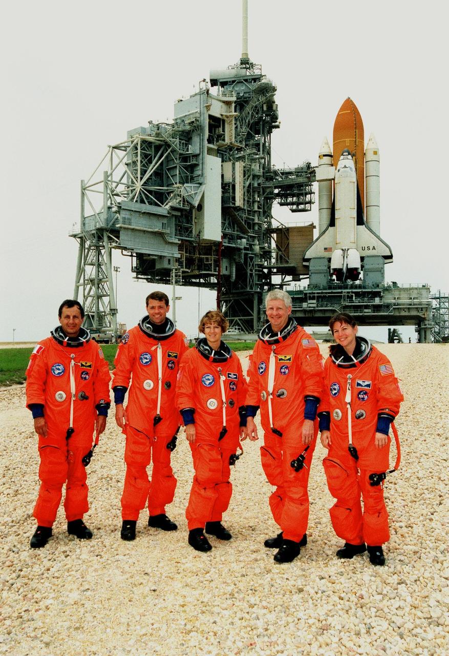 KENNEDY SPACE CENTER, FLA. -- The STS-93 crew pauses at the launch pad for a photograph before heading for Space Shuttle Columbia (in the background) and a launch-day dress rehearsal. From left are Mission Specialist Michel Tognini of France, who represents the Centre National d'Etudes Spatiales (CNES), Pilot Jeffrey S. Ashby, Commander Eileen M. Collins, and Mission Specialists Steven A. Hawley (Ph.D.) and Catherine G. Coleman (Ph.D.). Collins is the first woman to serve as a Shuttle commander. The crew members have been taking part in a Terminal Countdown Demonstration Test, which familiarizes them with the mission, provides training in emergency exit from the orbiter and launch pad, and includes the dress rehearsal culminating with a simulated main engine cut-off. The primary mission of STS-93 is the release of the Chandra X-ray Observatory, which will allow scientists from around the world to obtain unprecedented X-ray images of exotic environments in space to help understand the structure and evolution of the universe. The targeted launch date for STS-93 is no earlier than July 20 at 12:36 a.m. EDT from Launch Pad 39B