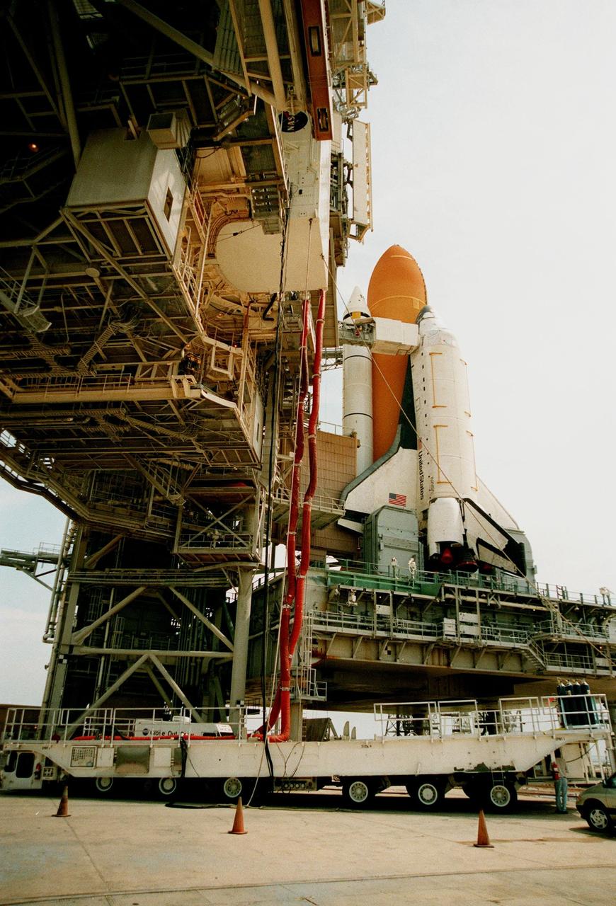 KENNEDY SPACE CENTER, FLA. -- At Launch Pad 39B, the payload canister carrying the Chandra X-ray Observatory begins its ascent up the Rotating Service Structure (RSS) to the Payload Changeout Room. Umbilical hoses, which maintain a controlled environment for the observatory, are still attached to the payload canister transporter below that transferred the observatory from the Vertical Processing Facility. The observatory will be moved into the payload bay of the Space Shuttle Columbia, seen in the background, after the RSS rotates to a position behind Columbia. The world's most powerful X-ray telescope, Chandra will allow scientists from around the world to see previously invisible black holes and high-temperature gas clouds, giving the observatory the potential to rewrite the books on the structure and evolution of our universe. Chandra is scheduled for launch no earlier than July 20 aboard Space Shuttle Columbia, on mission STS-93