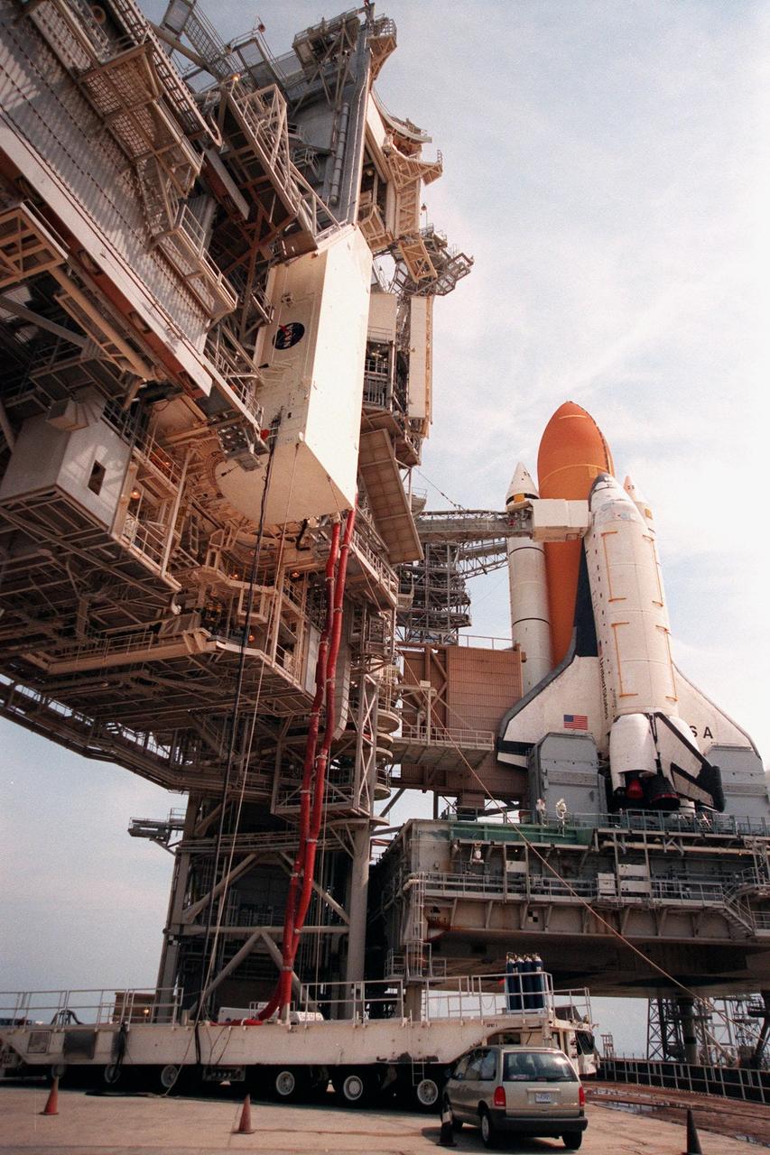 KENNEDY SPACE CENTER, FLA. -- At Launch Pad 39B, the payload canister carrying the Chandra X-ray Observatory nears the end of its ascent up the Rotating Service Structure (RSS) to the Payload Changeout Room. Umbilical hoses, which maintain a controlled environment for the observatory, are still attached to the payload canister transporter below that transferred the payload from the Vertical Processing Facility. The observatory will be moved into the payload bay of the Space Shuttle Columbia, seen in the background, after the RSS rotates to a position behind Columbia. The world's most powerful X-ray telescope, Chandra will allow scientists from around the world to see previously invisible black holes and high-temperature gas clouds, giving the observatory the potential to rewrite the books on the structure and evolution of our universe. Chandra is scheduled for launch no earlier than July 20 aboard Space Shuttle Columbia, on mission STS-93
