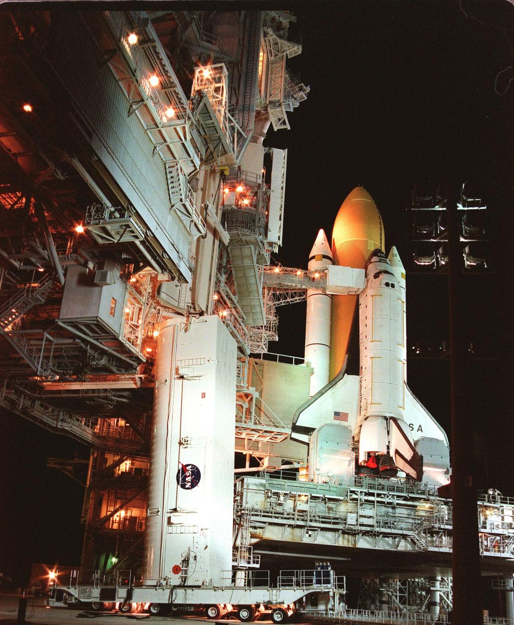 KENNEDY SPACE CENTER, FLA. -- The payload canister containing the Chandra X-ray Observatory is prepared for its ascent up the Rotating Service Structure (RSS). The canister arrived at the pad on the payload canister transporter below it. The canister will be lifted up to the Payload Changeout Room in the RSS where it will be relieved of its cargo. After the RSS rotates to a position behind Space Shuttle Columbia (at right), the observatory will then be installed vertically in the orbiter payload bay. The world's most powerful X-ray telescope, Chandra will allow scientists from around the world to see previously invisible black holes and high-temperature gas clouds, giving the observatory the potential to rewrite the books on the structure and evolution of our universe. Chandra is the primary payload on mission STS-93, scheduled to launch no earlier than July 20 aboard Space Shuttle Columbia (right)