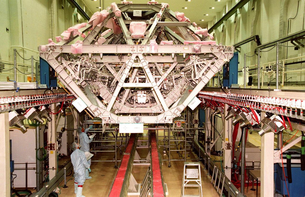 KENNEDY SPACE CENTER, FLA. -- Workers in the Operations & Checkout Bldg. (O&C) look over a central component of the International Space Station (ISS), the S0 (S zero) truss. It is undergoing processing in the O&C during which the Canadian Mobile Transporter, power distribution system modules, a heat pipe radiator for cooling, computers, and a pair of rate gyroscopes are being installed. A 44by 15-foot structure weighing 30,800 pounds when fully outfitted and ready for launch, the truss will ultimately extend the length of a football field. Eventually the S0 truss will be attached to the U.S. Lab, "Destiny," which is scheduled to be added to the ISS in April 2000. Later, other trusses will be attached to the S0 on-orbit. The S0 truss is scheduled to be launched in the spring of 2001