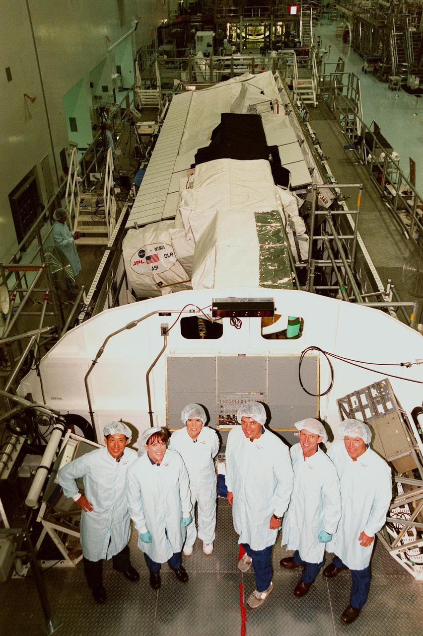 In the Space Station Processing Facility, the STS-99 crew pose in front of the Shuttle Radar Topography Mission, the payload for their mission. From left are Mission Specialists Mamoru Mohri of Japan, Janet Lynn Kavandi (Ph.D.), and Janice Voss (Ph.D.); Commander Kevin R. Kregel; Mission Specialist Gerhard Thiele of Germany; and Pilot Dominic L. Pudwill Gorie. Mohri represents the National Space Development Agency of Japan and Thiele represents the European Space Agency. An international project spearheaded by the National Imagery and Mapping Agency and NASA, with participation of the German Aerospace Center DLR, the SRTM consists of a specially modified radar system that will gather data for the most accurate and complete topographic map of the Earth's surface that has ever been assembled. SRTM will make use of radar interferometry, wherein two radar images are taken from slightly different locations. Differences between these images allow for the calculation of surface elevation, or change. The SRTM hardware will consist of one radar antenna in the shuttle payload bay and a second radar antenna attached to the end of a mast extended 60 meters (195 feet) out from the shuttle. STS-99 is scheduled to launch Sept. 16 at 8:47 a.m. from Launch Pad 39A