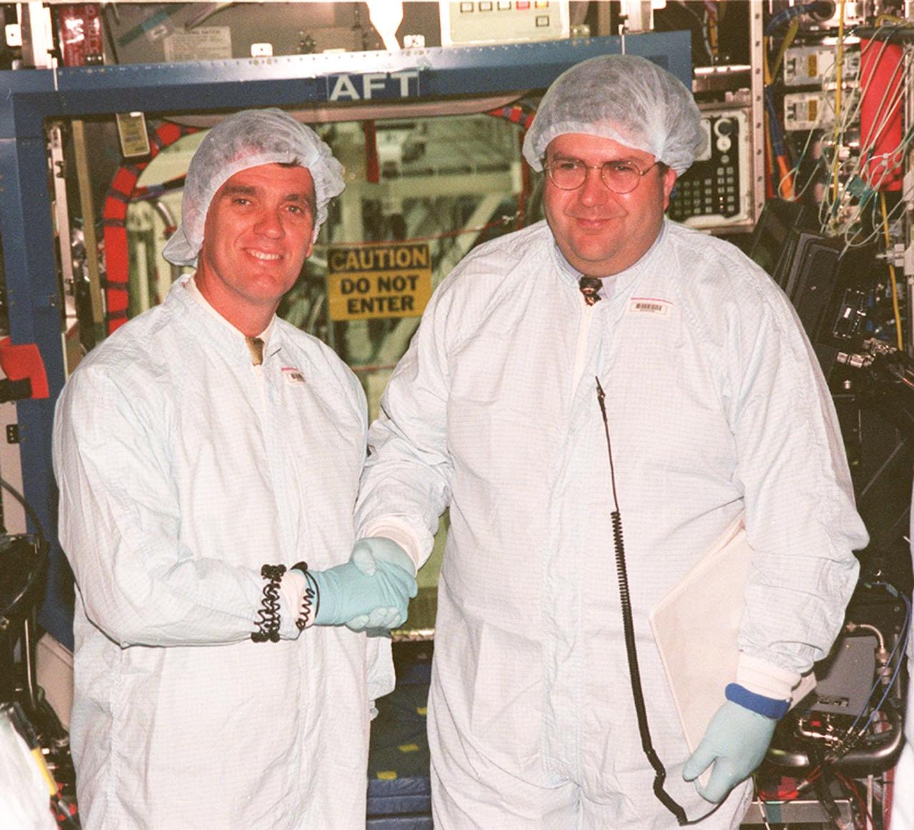 KENNEDY SPACE CENTER, FLA. -- Standing in front of the U.S. Lab, named Destiny, U.S. Rep. Dave Weldon (left) thanks Thomas R. "Randy" Galloway, with the Space Station Hardware Integration Office, for briefing him on the equipment inside the Lab. Weldon is on the House Science Committee and vice chairman of the Space and Aeronautics Subcommittee. Destiny is scheduled to be launched on Space Shuttle Endeavour in early 2000. It will become the centerpiece of scientific research on the ISS, with five equipment racks aboard to provide essential functions for station systems, including high data-rate communications, and to maintain the station's orientation using control gyroscopes launched earlier. Additional equipment and research racks will be installed in the laboratory on subsequent Shuttle flights