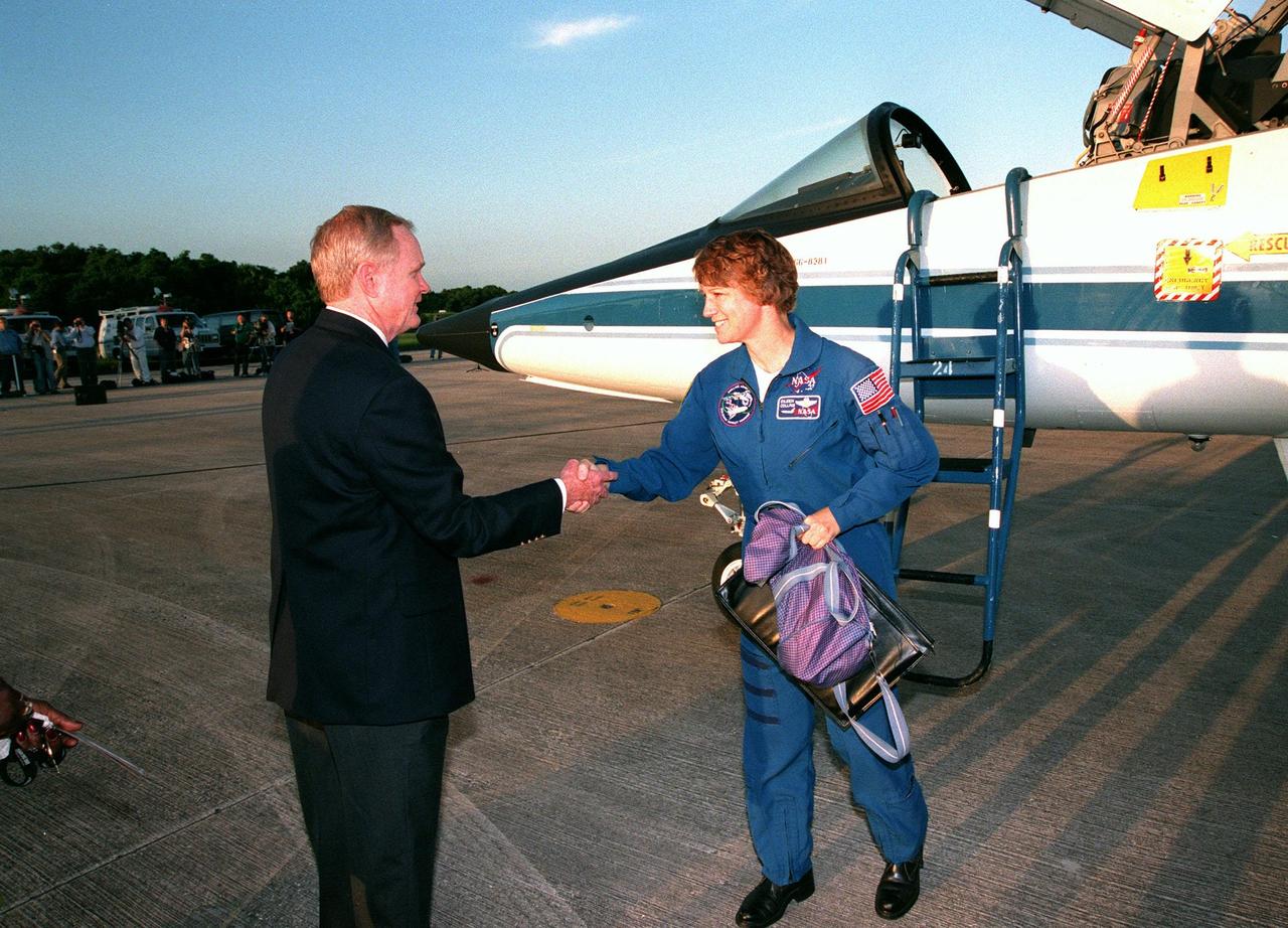 Center Director Roy D. Bridges Jr. greets STS-93 Commander Eileen M. Collins after her arrival at KSC's Shuttle Landing Facility aboard a T-38 jet aircraft (behind her). She and other crew members Pilot Jeffrey S. Ashby and Mission Specialists Steven A. Hawley (Ph.D.), Catherine G. "Cady" Coleman (Ph.D.) and Michel Tognini of France, with the Centre National d'Etudes Spatiales (CNES), are arriving for pre-launch activities. Collins is the first woman to serve as mission commander. This is her third Shuttle flight. The primary mission of STS-93 is the release of the Chandra X-ray Observatory, which will allow scientists from around the world to study some of the most distant, powerful and dynamic objects in the universe. The new telescope is 20 to 50 times more sensitive than any previous X-ray telescope and is expected to unlock the secrets of supernovae, quasars and black holes