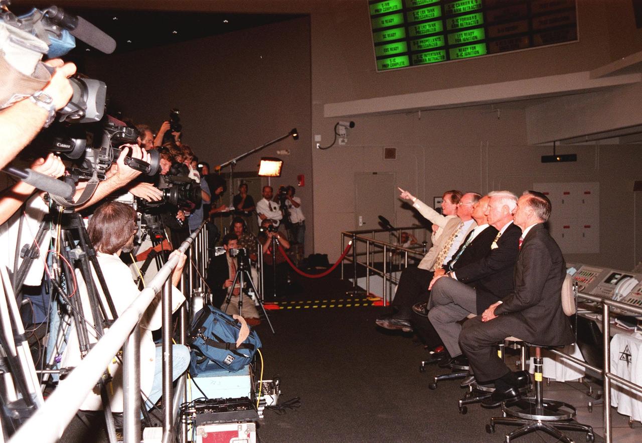 KENNEDY SPACE CENTER, FLA. -- In the Apollo/Saturn V Center, Lisa Malone, chief of KSC's Media Services branch, identifies a reporter in the stands to pose a question to one of the former Apollo astronauts seated next to her. From left to right, they are Neil A. Armstrong and Edwin "Buzz" Aldrin who flew on Apollo 11, the launch to the moon; Gene Cernan, who flew on Apollo 10 and 17; and Walt Cunningham, who flew on Apollo 7. Behind them on the lower floor are the original computer consoles used in the firing room during the Apollo program. They are now part of the reenactment of the Apollo launches in the exhibit at the center. This is the 30th anniversary of the launch and moon landing, July 16 and July 20, 1969. Neil Armstrong was the first man to set foot on the moon