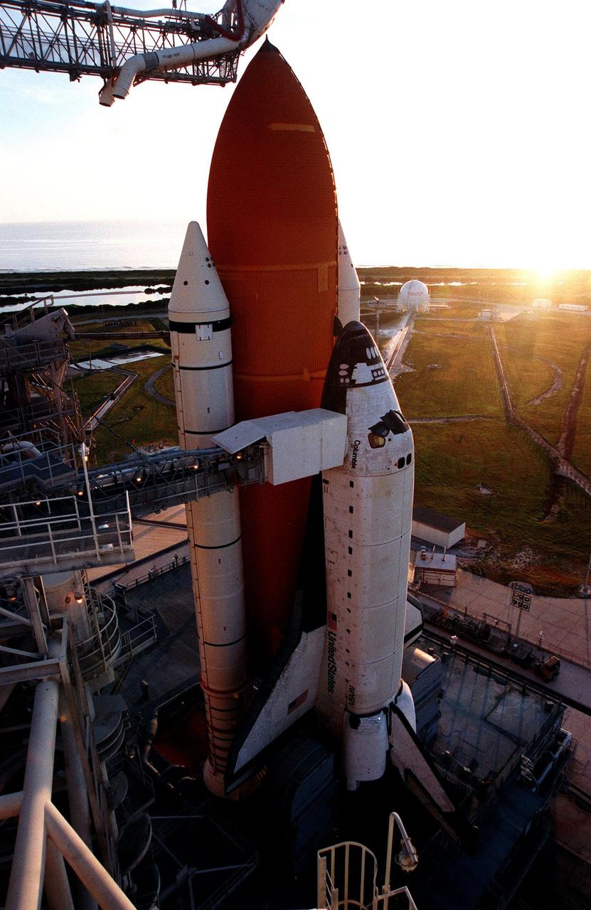 Space Shuttle Columbia catches the rising sun after the rollback of the Rotating Service Structure on Launch Pad 39-B. Columbia waits for the launch of mission STS-93 July 20 at 12:36 a.m. EDT. The primary payload of STS-93 is the Chandra X-ray Observatory, which will allow scientists from around the world to study some of the most distant, powerful and dynamic objects in the universe. The new telescope is 20 to 50 times more sensitive than any previous X-ray telescope and is expected unlock the secrets of supernovae, quasars and black holes. The STS-93 crew numbers five: Commander Eileen M. Collins, Pilot Jeffrey S. Ashby, and Mission Specialists Steven A. Hawley (Ph.D.), Catherine G. Coleman (Ph.D.) and Michel Tognini of France, with the Centre National d'Etudes Spatiales (CNES). Collins is the first woman to serve as commander of a shuttle mission