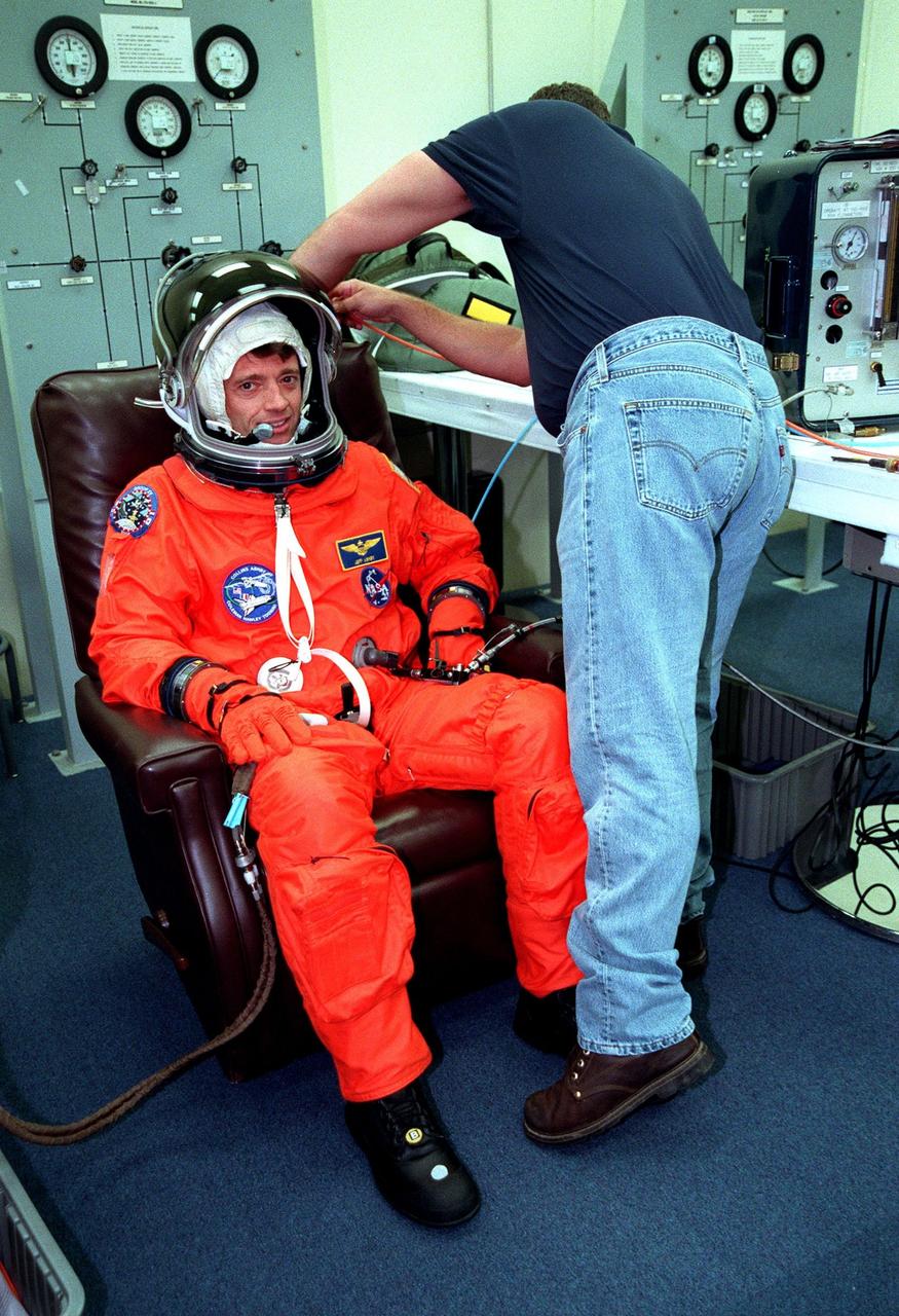 In the Operations and Checkout Building during final launch preparations, STS-93 Pilot Jeffrey S. Ashby waits after donning his launch and entry suit while a suit tech adjusts his helmet. STS-93 is a five-day mission primarily to release the Chandra X-ray Observatory, which will allow scientists from around the world to study some of the most distant, powerful and dynamic objects in the universe. The new telescope is 20 to 50 times more sensitive than any previous X-ray telescope and is expected unlock the secrets of supernovae, quasars and black holes. The STS-93 crew numbers five: Commander Eileen M. Collins, Ashby, and Mission Specialists Stephen A. Hawley (Ph.D.), Catherine G. Coleman (Ph.D.) and Michel Tognini of France, with the Centre National d'Etudes Spatiales (CNES). Collins is the first woman to serve as commander of a shuttle mission. STS-93 is scheduled to lift off at 12:36 a.m. EDT July 20. The target landing date is July 24 at 11:30 p.m. EDT