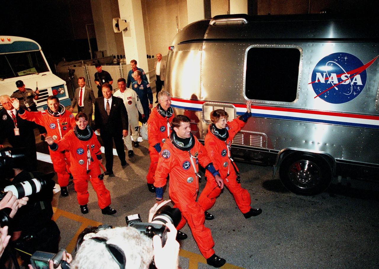 The STS-93 crew wave to onlookers as they walk to the "Astrovan," which will transport them to Launch Pad 39-B and liftoff of Space Shuttle Columbia. In their orange launch and entry suits, they are (starting at rear, left to right) Mission Specialists Michel Tognini of France, who represents the Centre National d'Etudes Spatiales (CNES), Catherine G. Coleman (Ph.D.), and Mission Specialist Stephen A. Hawley (Ph.D.); Pilot Jeffrey S. Ashby; and Commander Eileen M. Collins. STS-93 is a five-day mission primarily to release the Chandra X-ray Observatory, which will allow scientists from around the world to study some of the most distant, powerful and dynamic objects in the universe. The new telescope is 20 to 50 times more sensitive than any previous X-ray telescope and is expected unlock the secrets of supernovae, quasars and black holes. Collins is the first woman to serve as commander of a Shuttle mission. STS-93 is scheduled to lift off at 12:36 a.m. EDT July 20. The target landing date is July 24 at 11:31 p.m. EDT